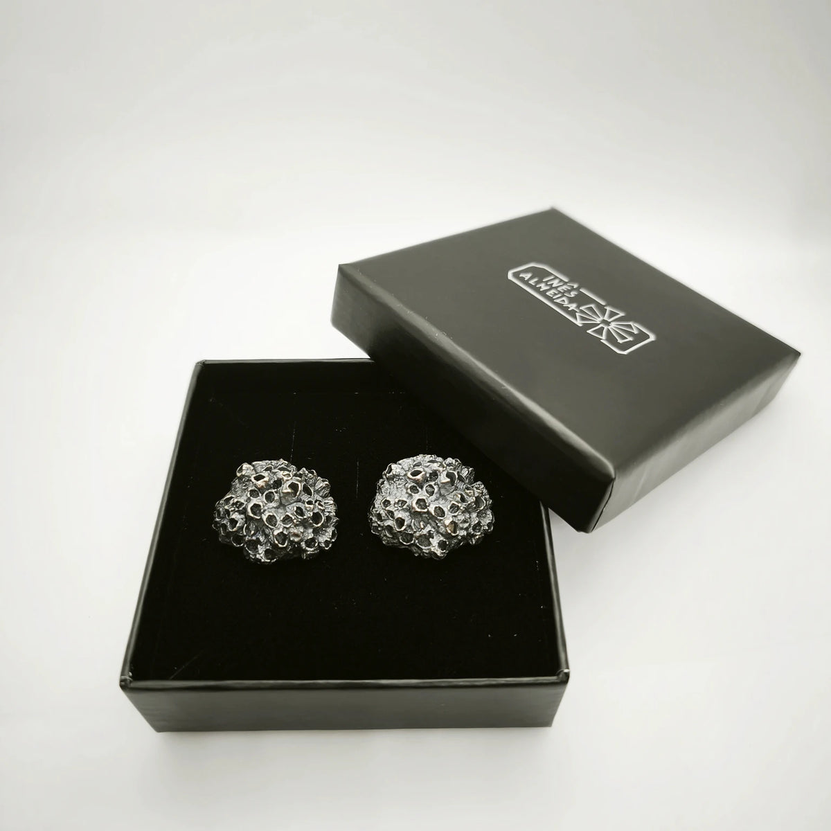 Handcrafted 925 sterling oxidized silver earrings with organic texture inspired by marine barnacles, set in a jewellery box. Piece by Inês Almeida Jewellery