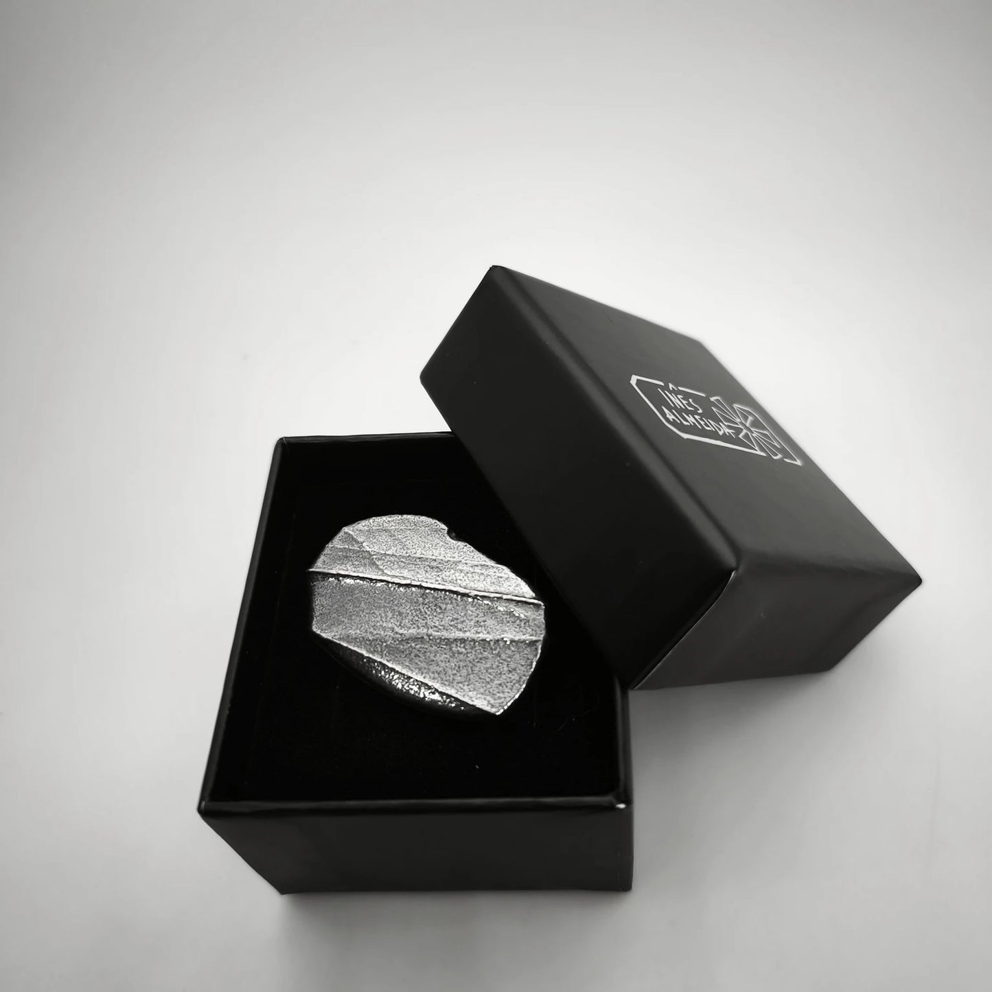 925 sterling silver oxidised ring with the texture from small pebble in a jewellery black box. Design by Inês Almeida