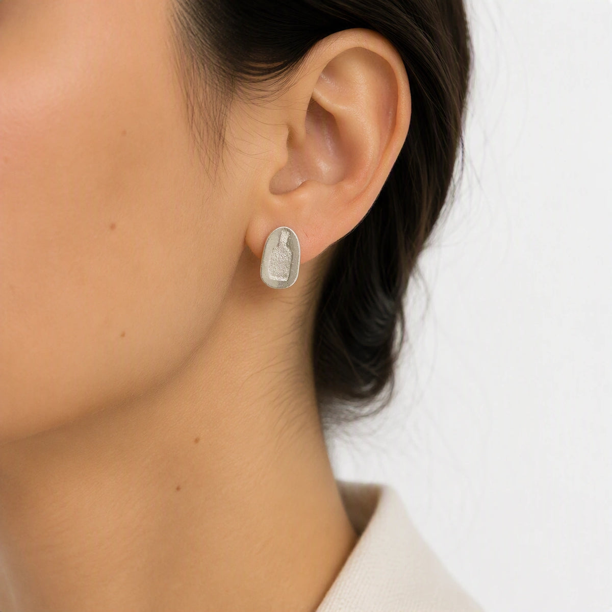 Sterling silver earring featuring a jug motif worn on the left ear, shown in a close-up contemporary jewellery portrait against a soft white background, from the At the Table with Morandi collection by Inês Almeida.