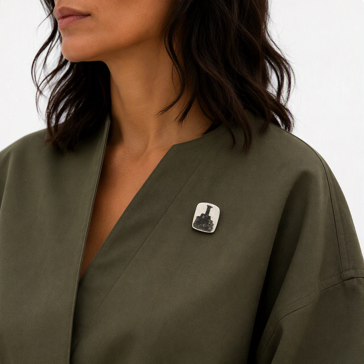 Sterling silver pin featuring a bottle motif worn on an olive-green contemporary garment, from the At the Table with Morandi collection.