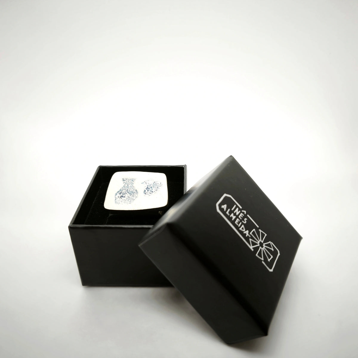 Sterling silver ring featuring two jug motifs presented in an open black jewellery box by Inês Almeida.