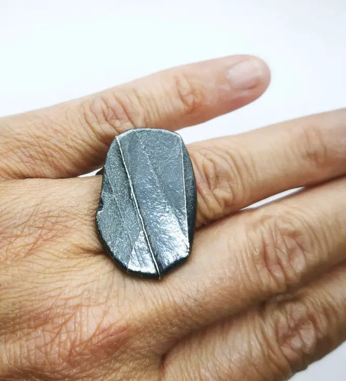 Woman wearing a 925 sterling silver oxidised ring with the texture from small pebble. Design by Inês Almeida