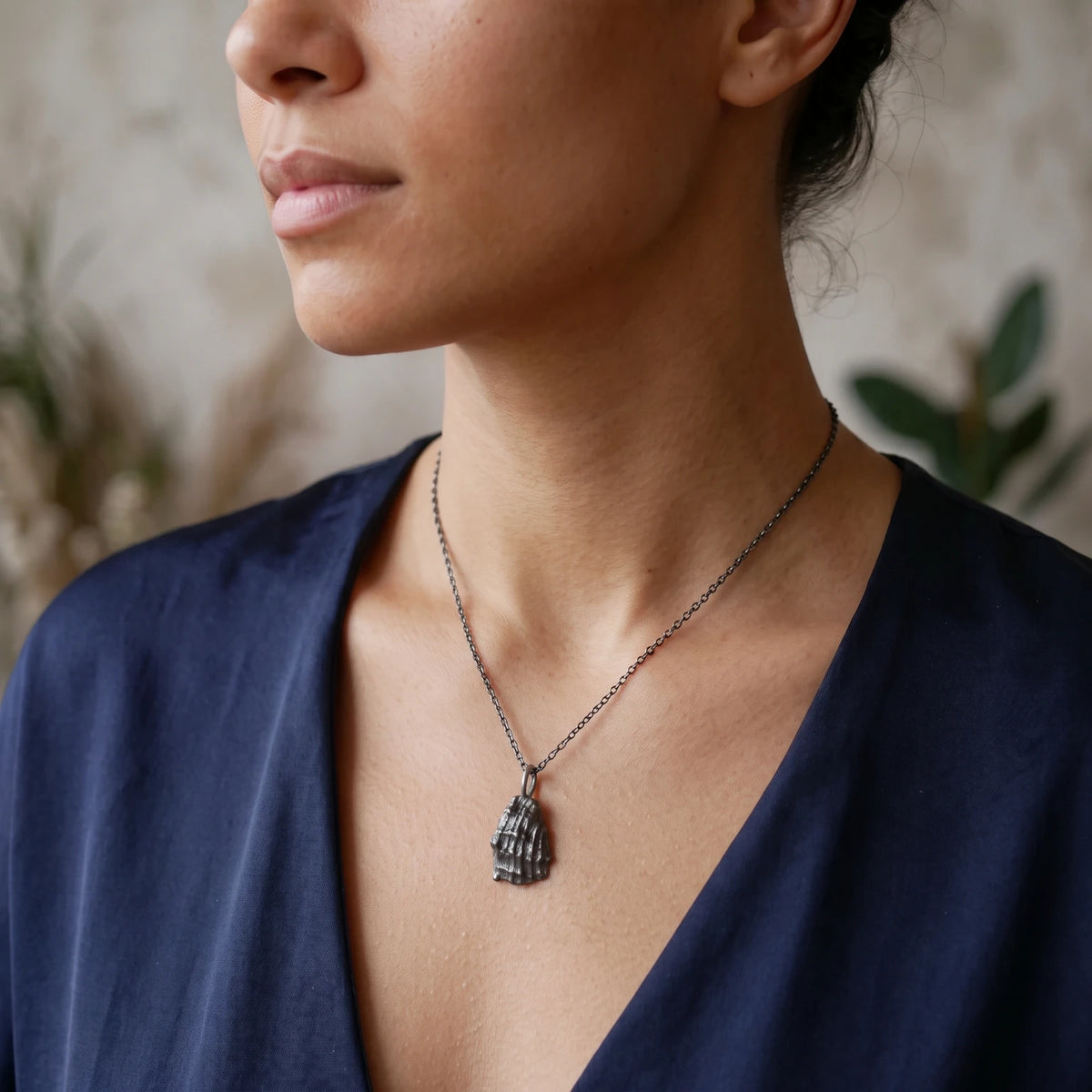 Woman wearing a 925 sterling silver oxidised pendant with the texture from a conch shell. Design by Inês Almeida