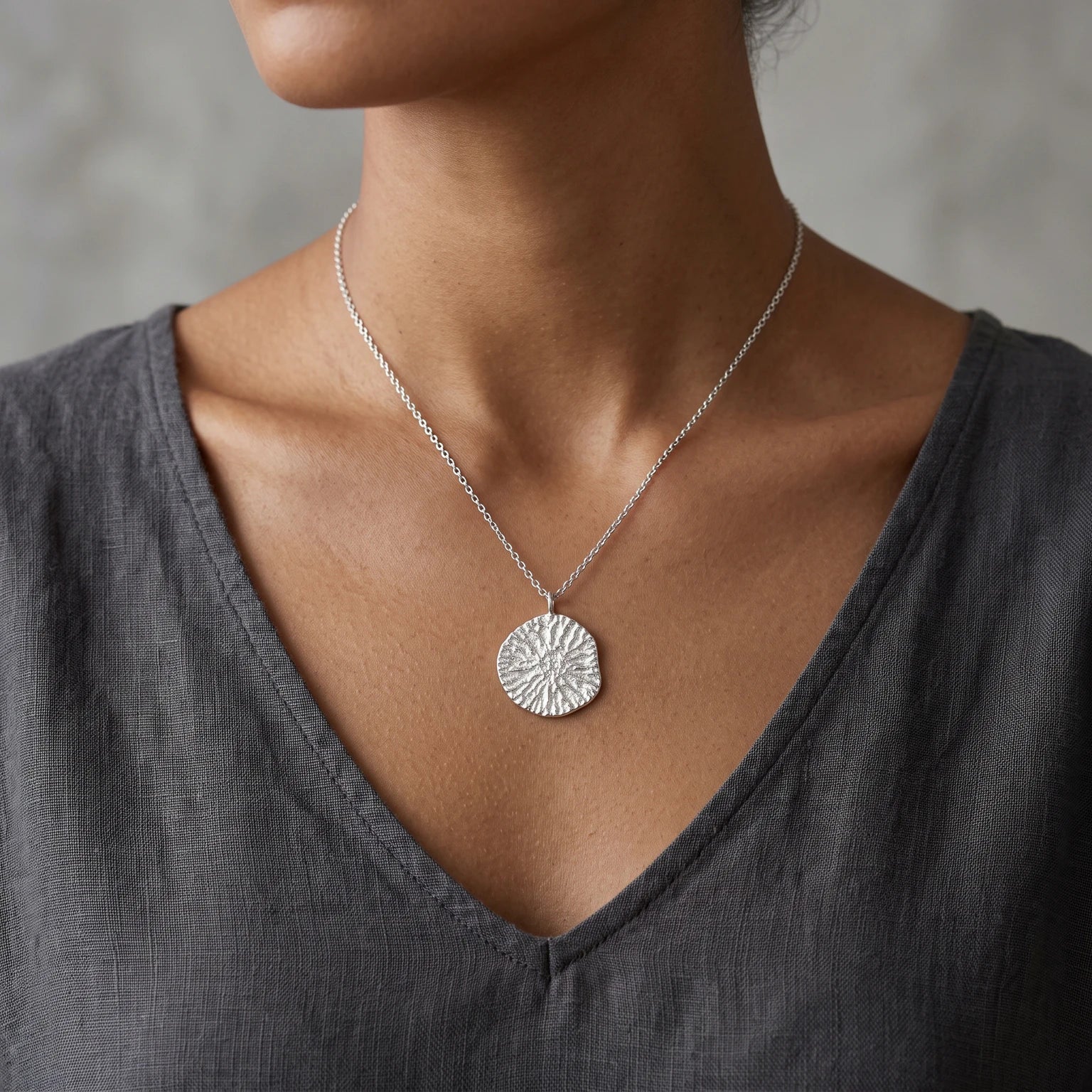 A female model wearing 925 sterling silver pendant with the texture from a dolphin spine bone. Design by Inês Almeida.