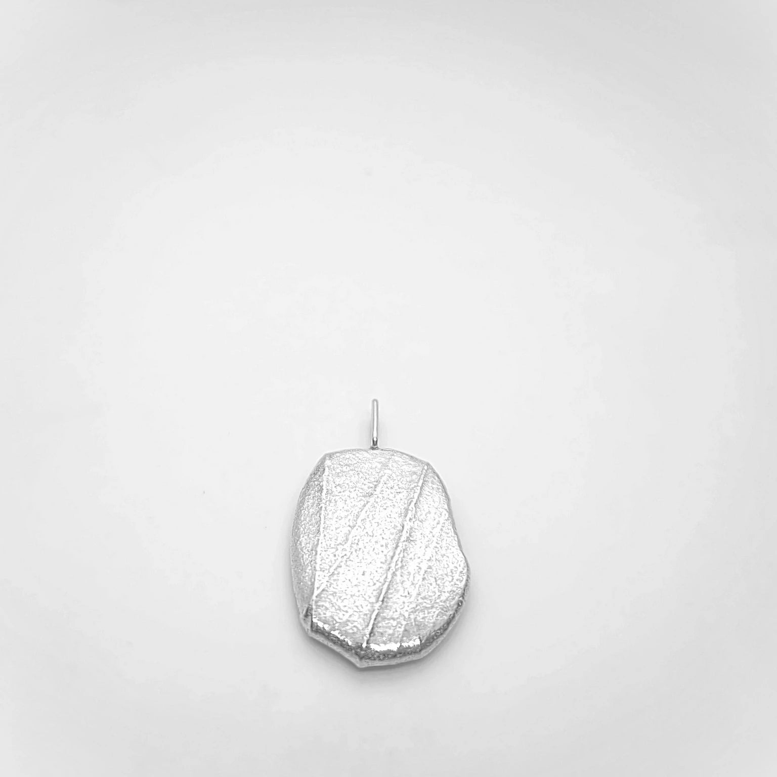 Woman wearing 925 sterling silver pendant with the texture from a pebble. Design by Inês Almeida
