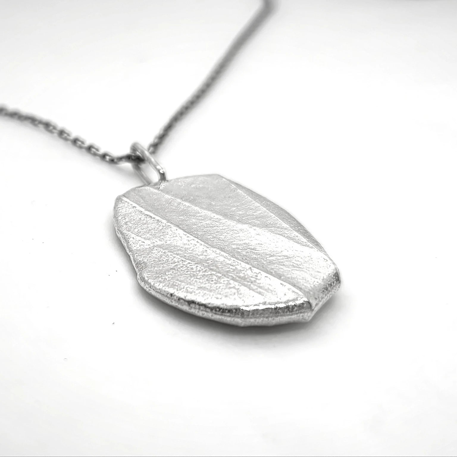 Woman wearing 925 sterling silver pendant with the texture from a pebble. Design by Inês Almeida