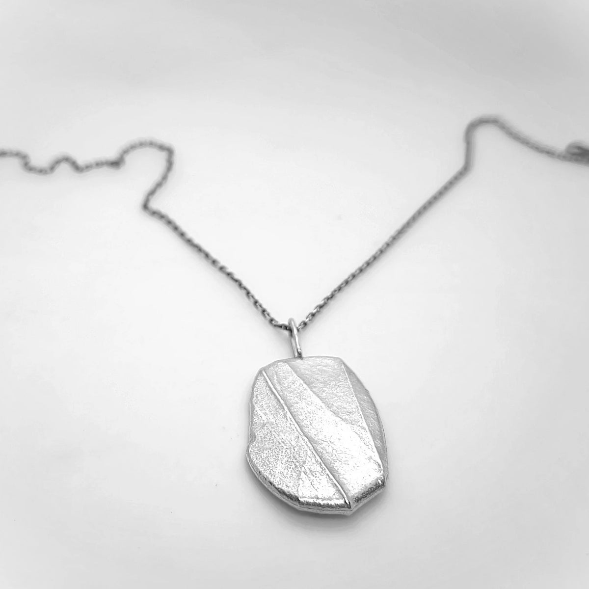 Woman wearing 925 sterling silver pendant with the texture from a pebble. Design by Inês Almeida