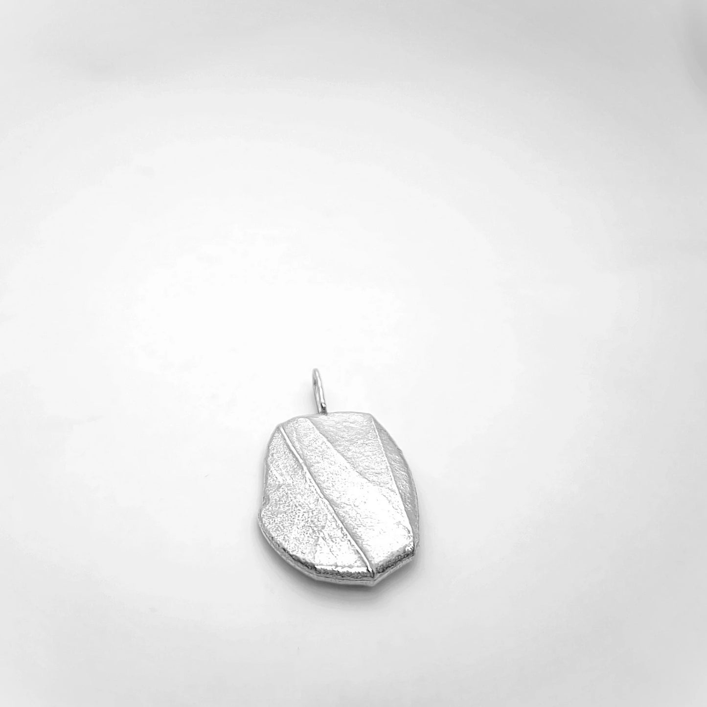 Woman wearing 925 sterling silver pendant with the texture from a pebble. Design by Inês Almeida