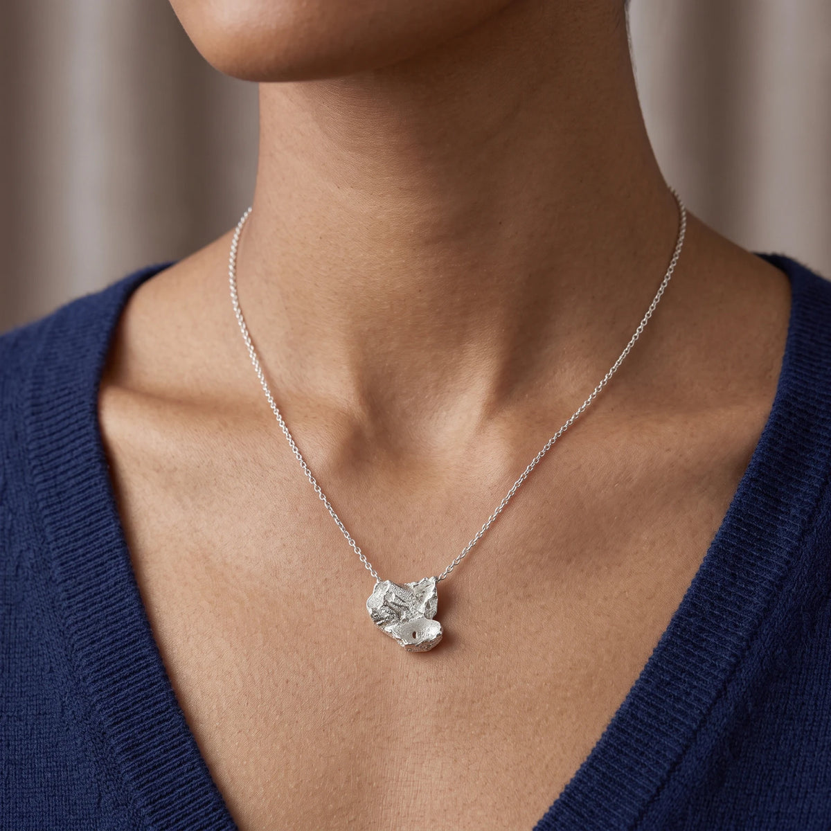 Woman wearing a 925 sterling silver pendant with the texture from barnacles in a jewellery black box. Design by Inês Almeida.