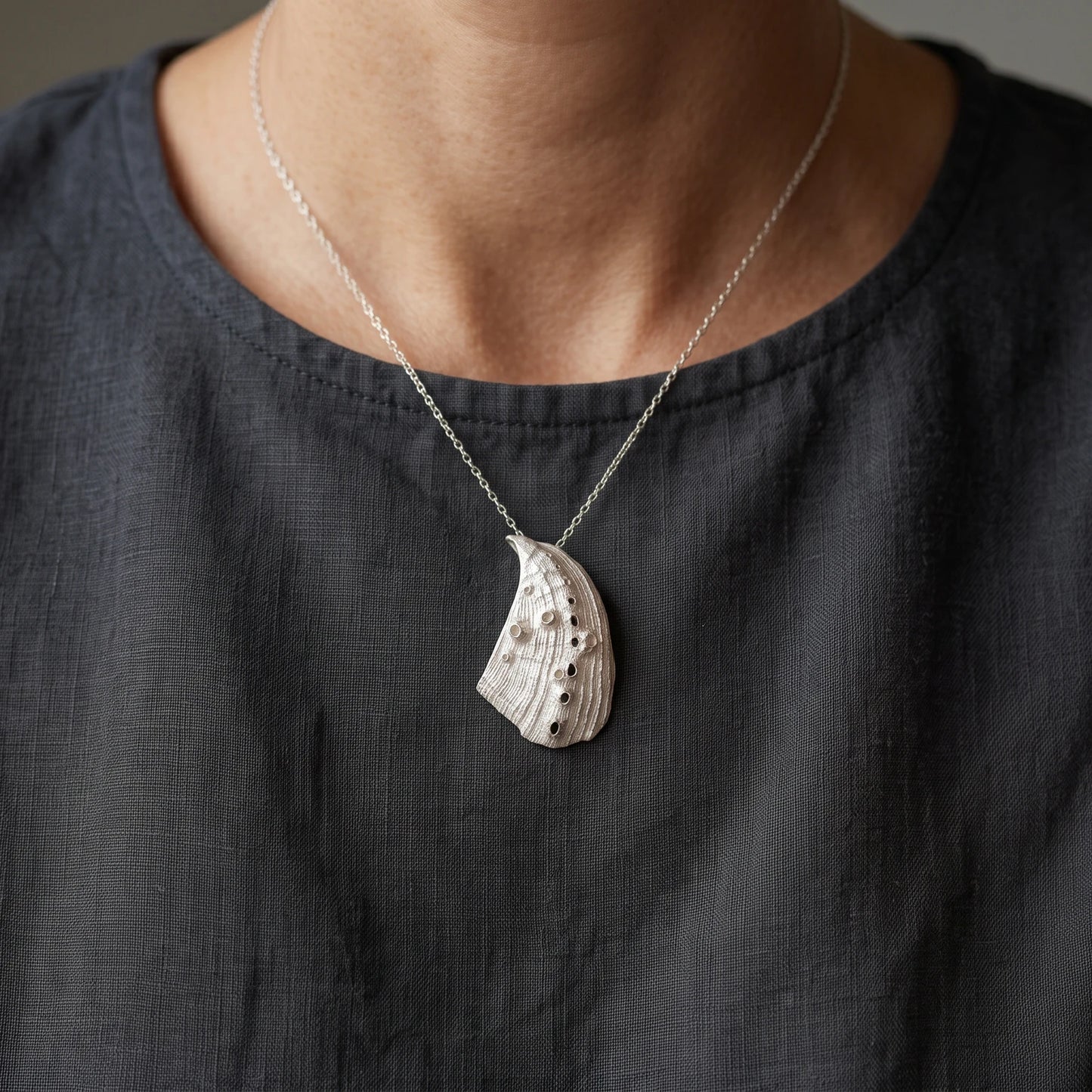 Woman wearing a 925 sterling silver pendent with the texture from a Fragment of an abalone. Design by Inês Almeida