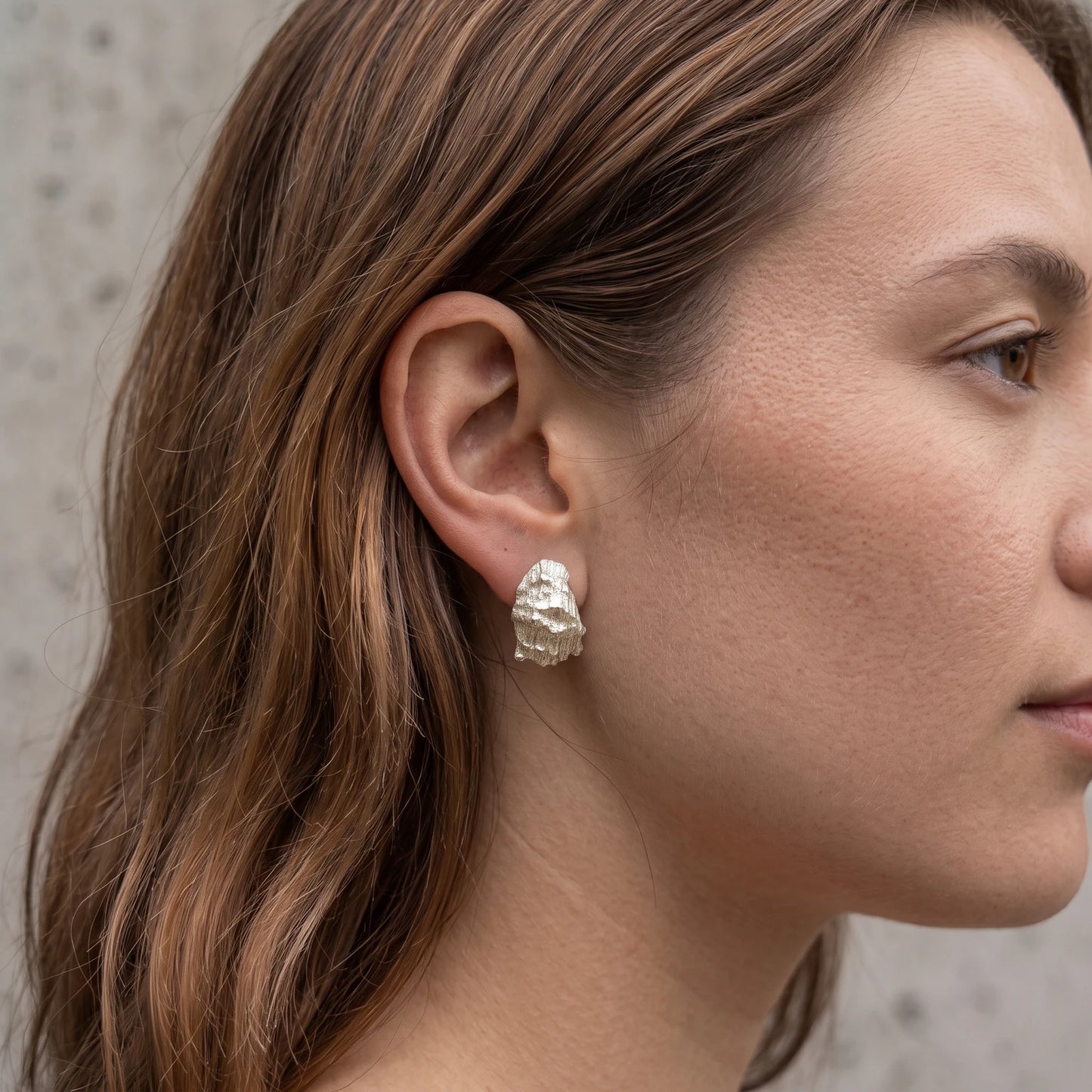A female model wearing 925 sterling silver earrings with the texture from a conch shell. Design by Inês Almeida.