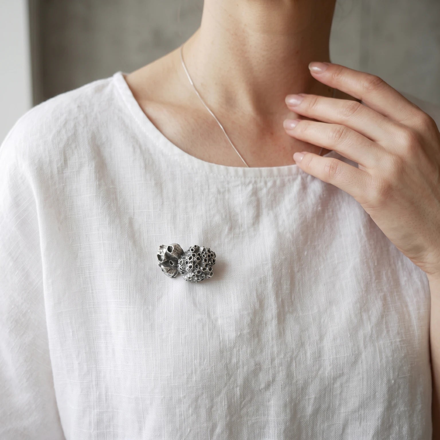Woman wearing a 925 sterling oxidised silver brooch with the texture from a barnacle. Design by Inês Almeida