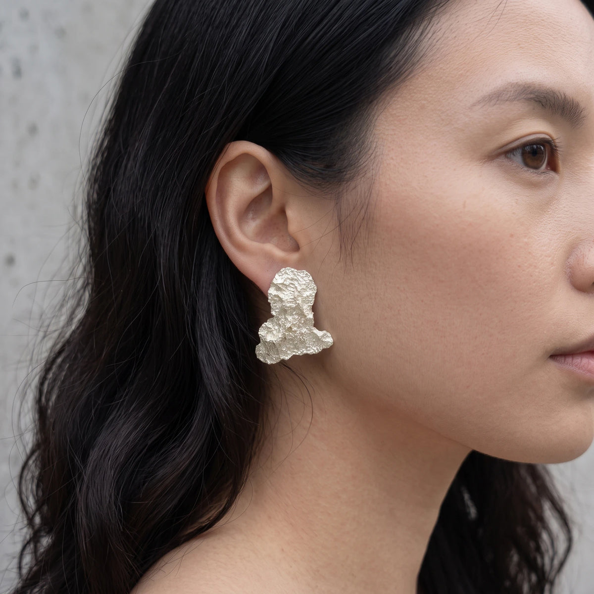 A female model wearing 925 sterling silver earrings with the texture from an algae. Design by Inês Almeida.