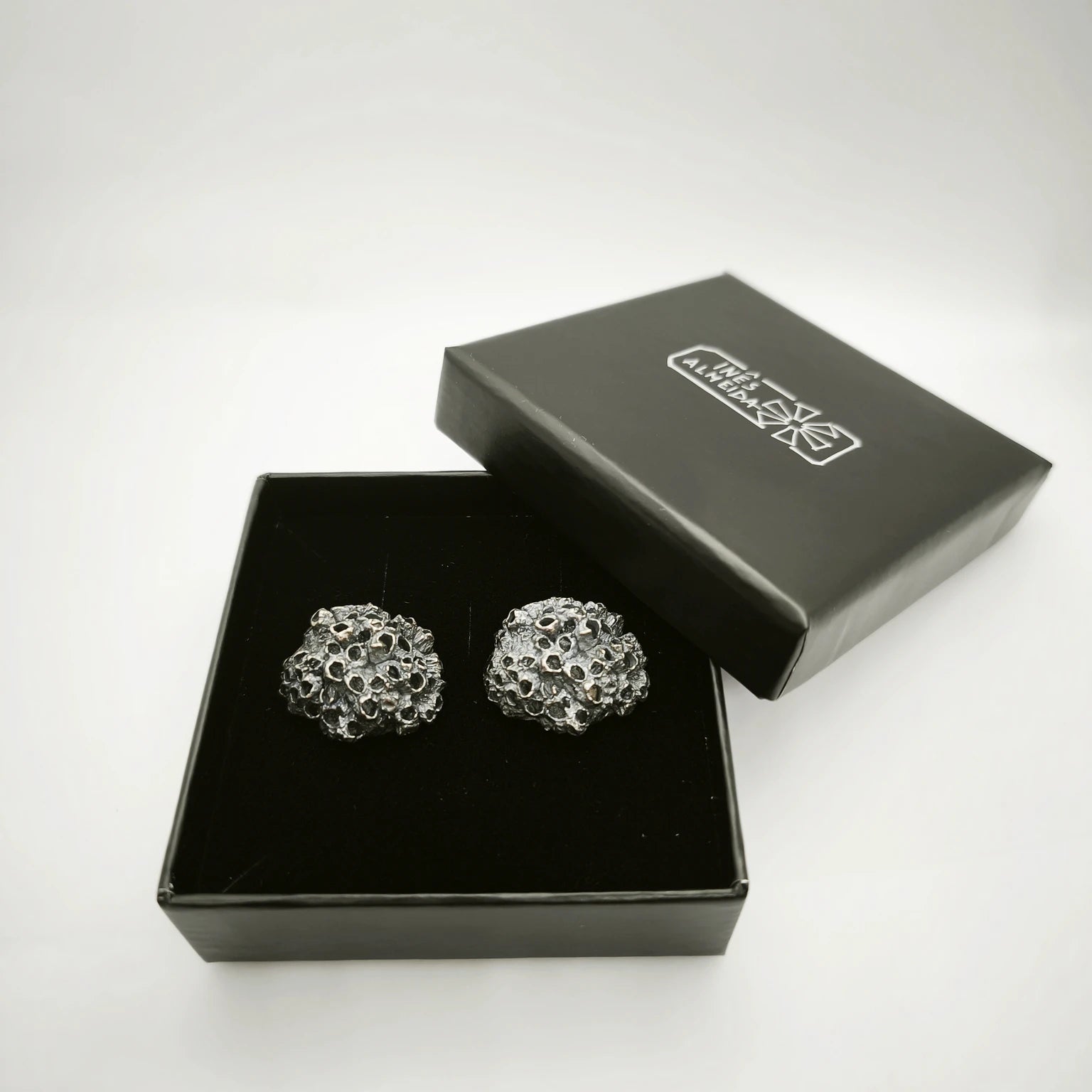 Handcrafted 925 sterling oxidized silver earrings with organic texture inspired by marine barnacles, set in a jewellery box. Piece by Inês Almeida Jewellery