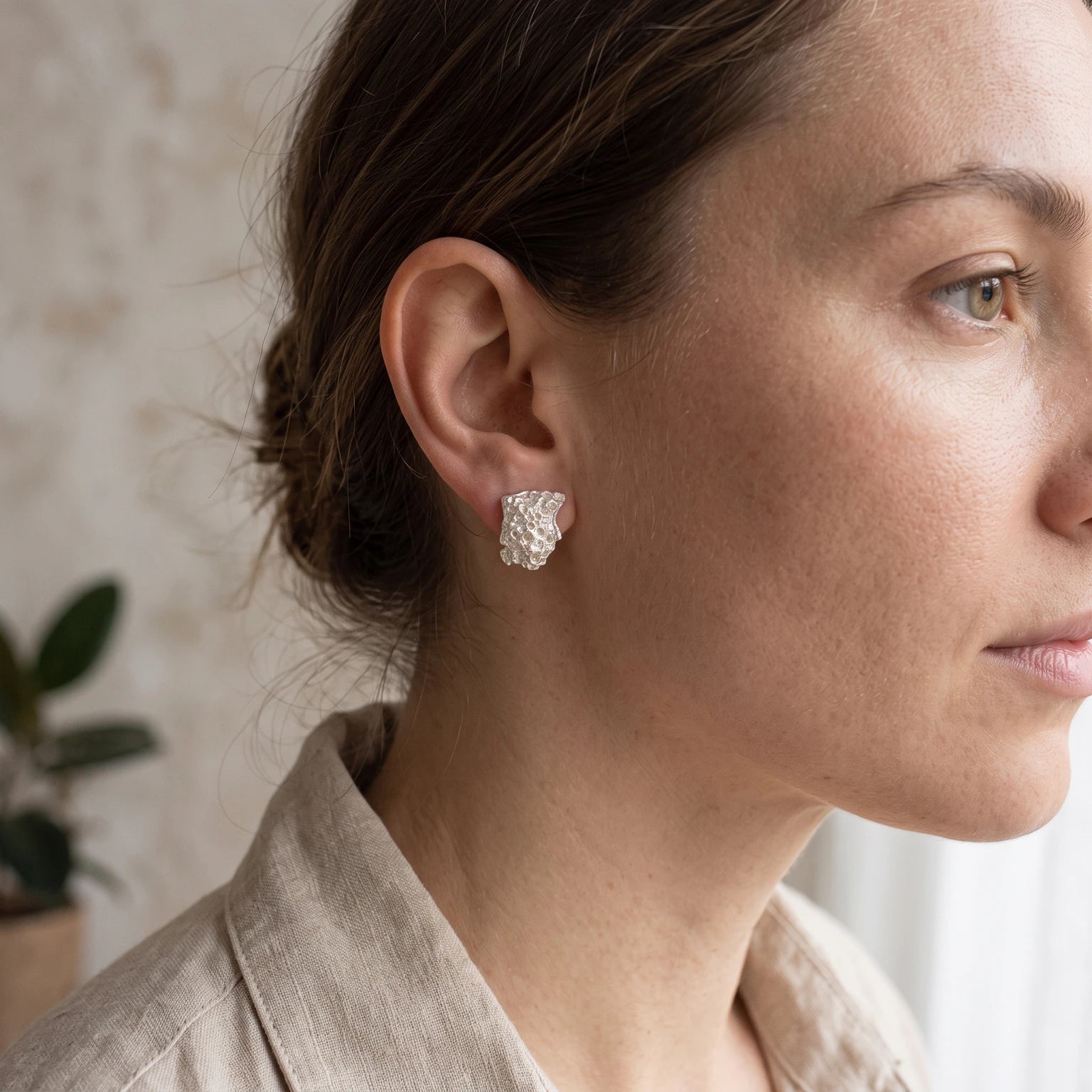 A female model wearing 925 sterling silver earrings with the texture from a coraline. Design by Inês Almeida.