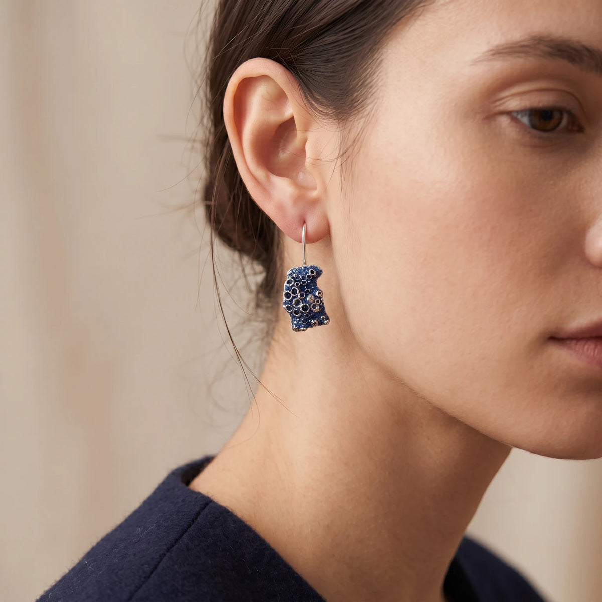 A female model wearing 925 sterling silver earrings barnacle painted with blue. Design by Inês Almeida.