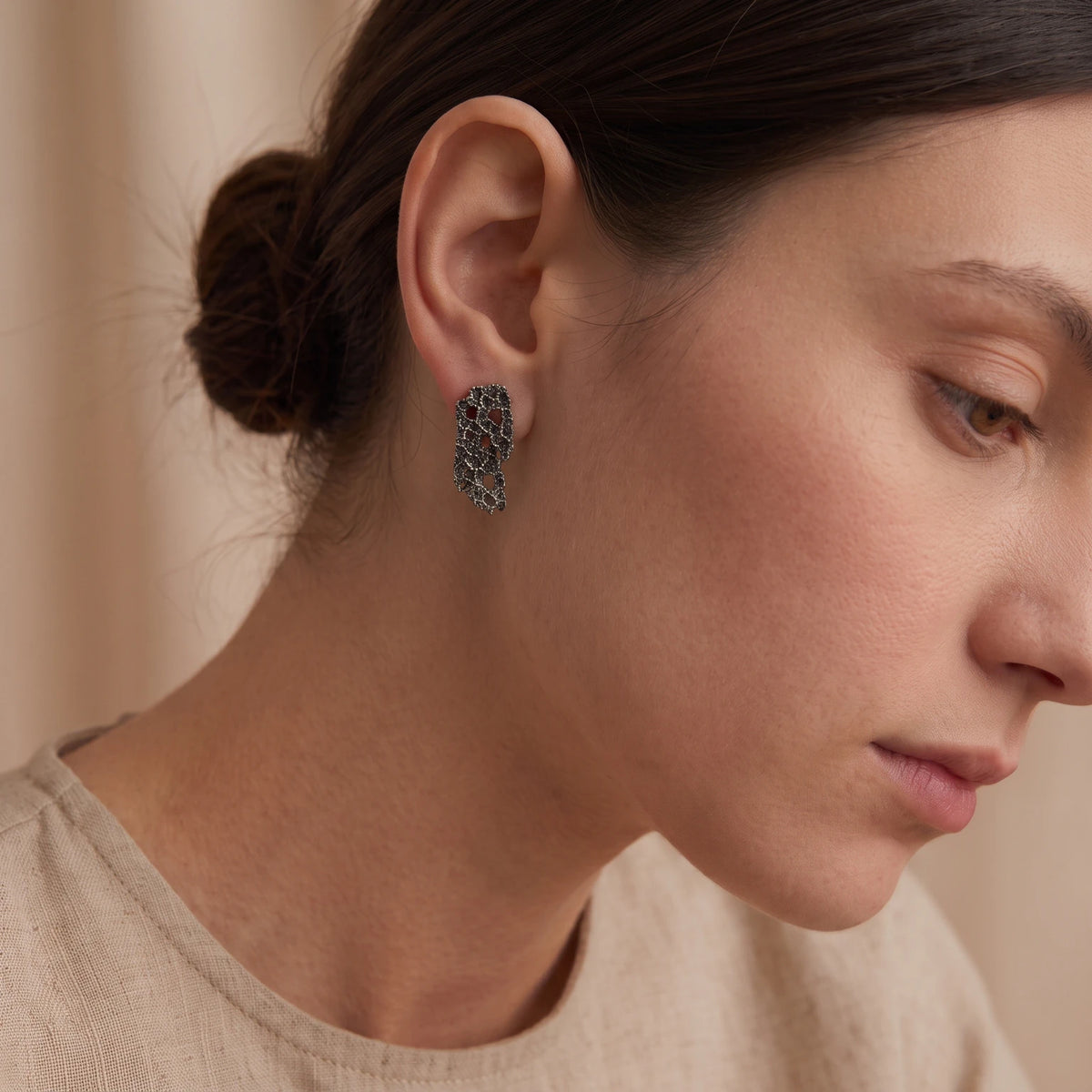A female model wearing 925 sterling oxidised silver earrings with the texture from a coraline. Design by Inês Almeida.