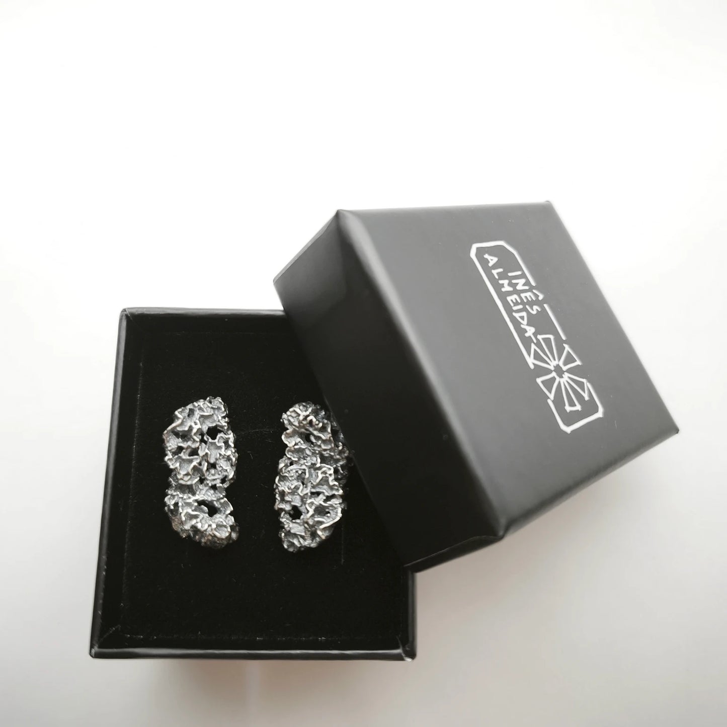 925 sterling oxidised silver earrings with the texture from a coraline in a black jewellery box. Design by Inês Almeida