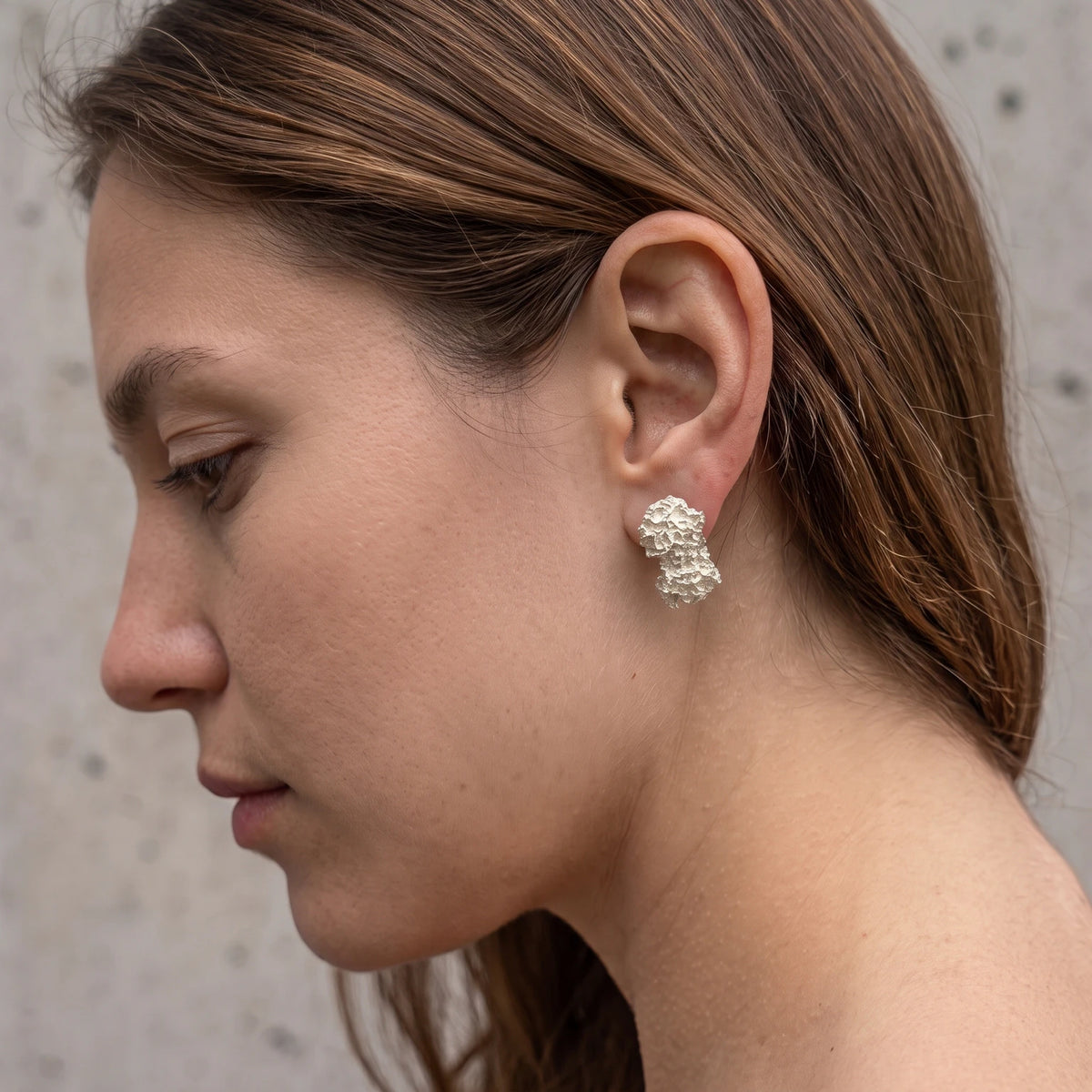 A female model wearing 925 sterling silver earrings with the texture from a coraline. Design by Inês Almeida.