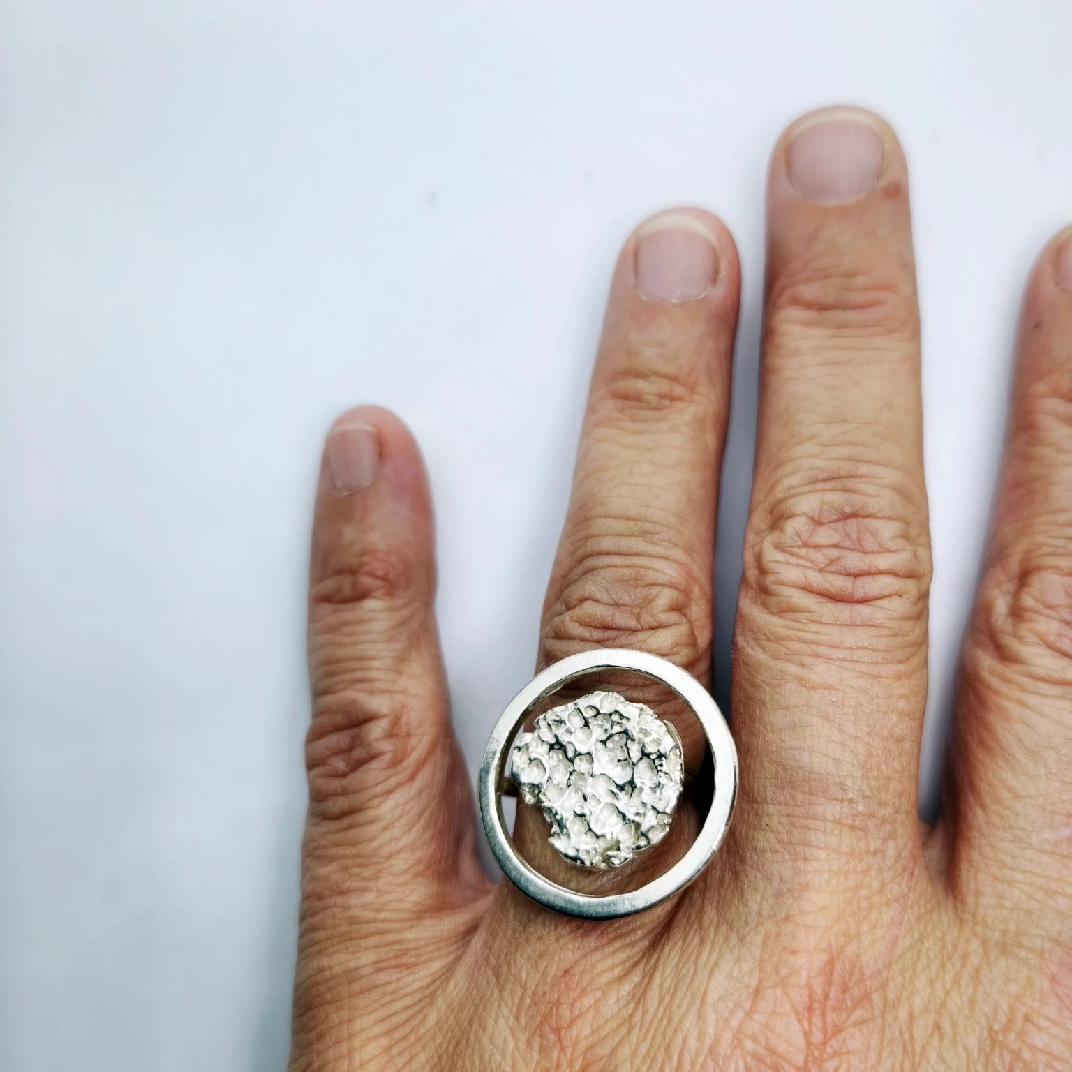 Woman wearing a 925 sterling silver ring with the texture from a rock fragment. Design by Inês Almeida