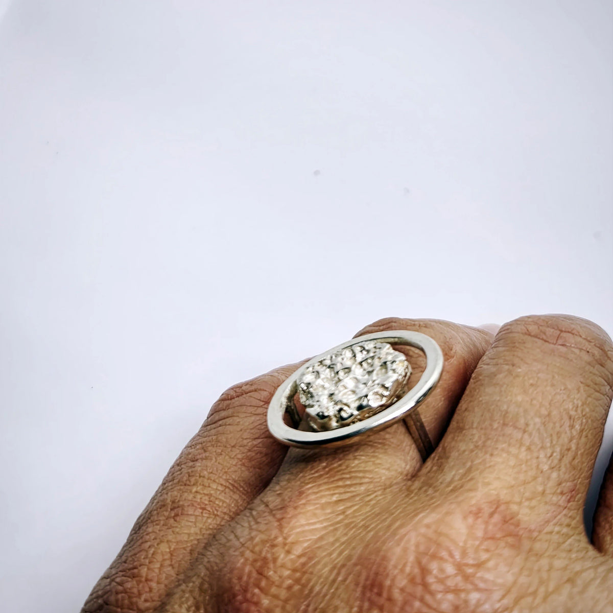 Woman wearing a 925 sterling silver ring with the texture from a rock fragment. Design by Inês Almeida