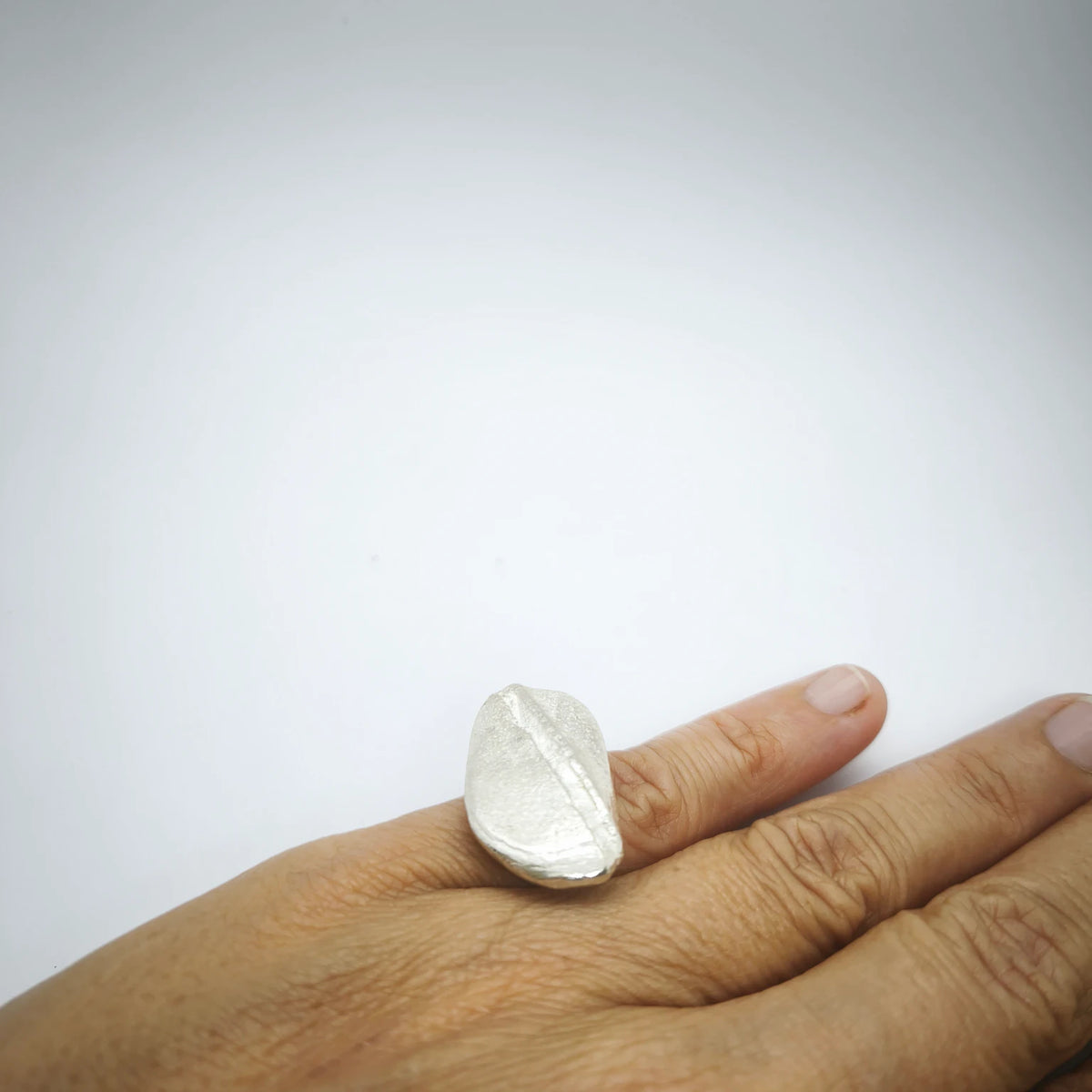 Woman wearing a 925 sterling silver ring with the texture from a pebble. Design by Inês Almeida