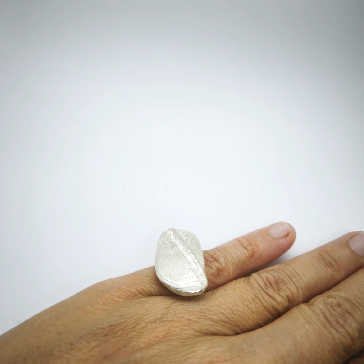 Woman wearing a 925 sterling silver ring with the texture from a pebble. Design by Inês Almeida