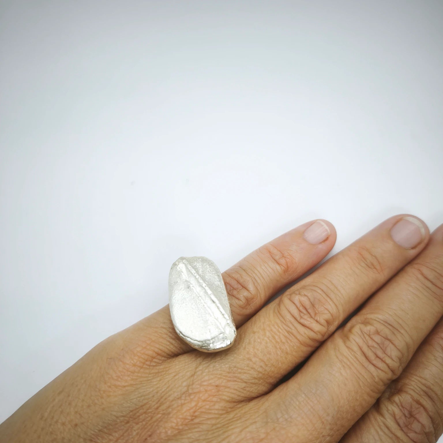Woman wearing a 925 sterling silver ring with the texture from a pebble. Design by Inês Almeida