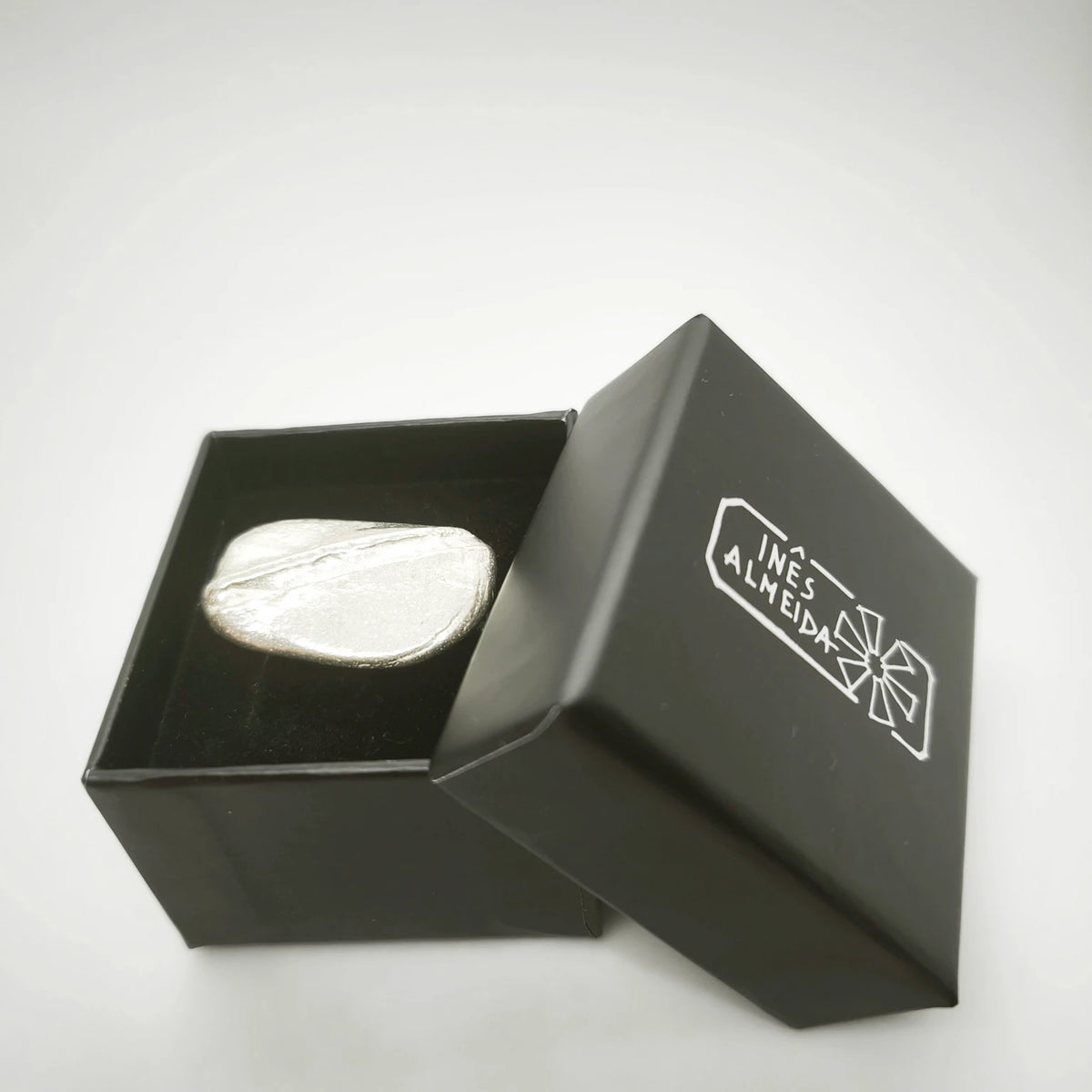 925 sterling silver ring with the texture from a pebble in a jewellery back box. Design by Inês Almeida