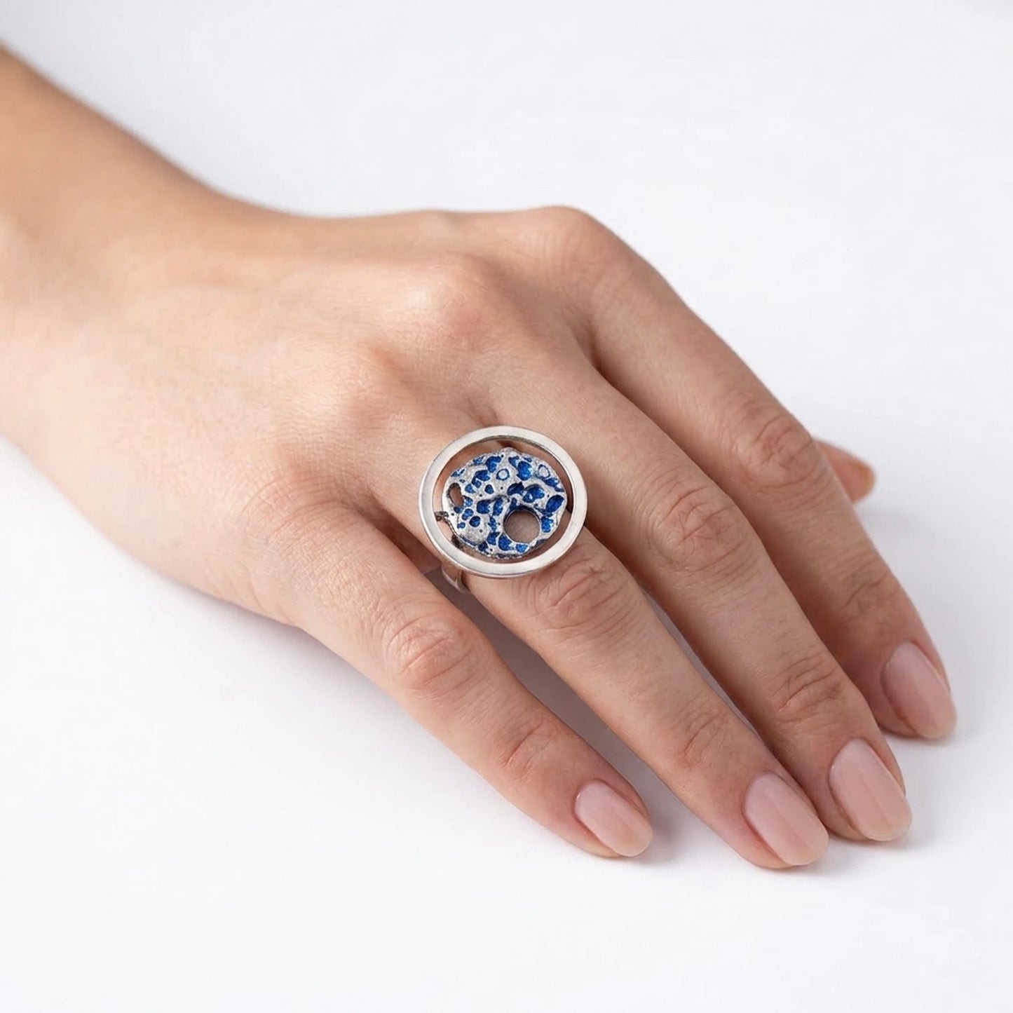 woman wearing a 925 sterling silver blue ring with the texture from a conch shell. Design by Inês Almeida