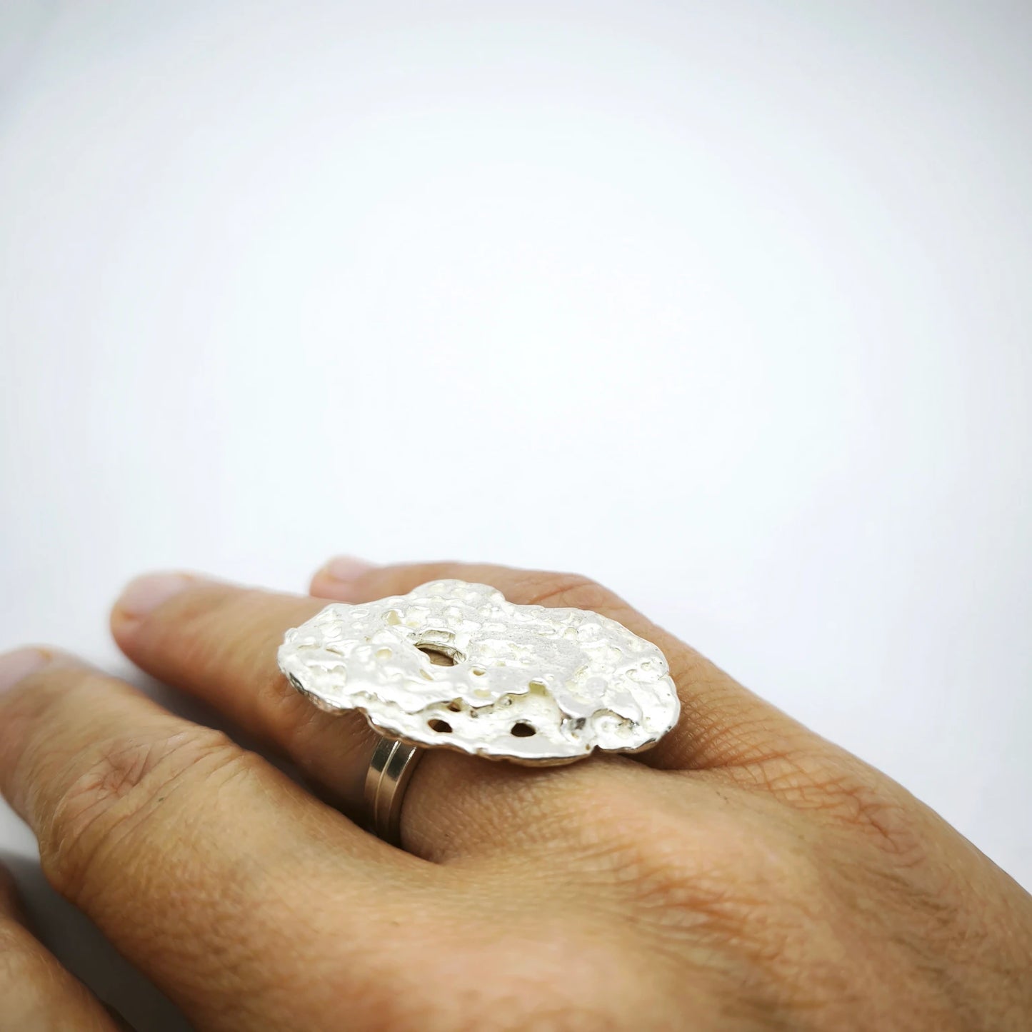 Woman wearing a 925 sterling silver ring with the texture from pebble. Design by Inês Almeida