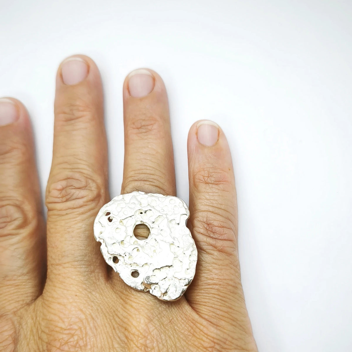 Woman wearing a 925 sterling silver ring with the texture from pebble. Design by Inês Almeida