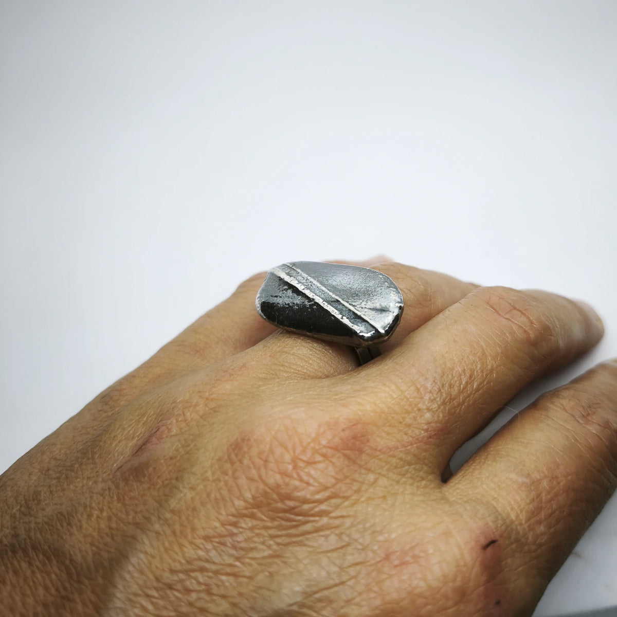 Woman wearing a 925 sterling silver oxidised ring with the texture from small pebble. Design by Inês Almeida