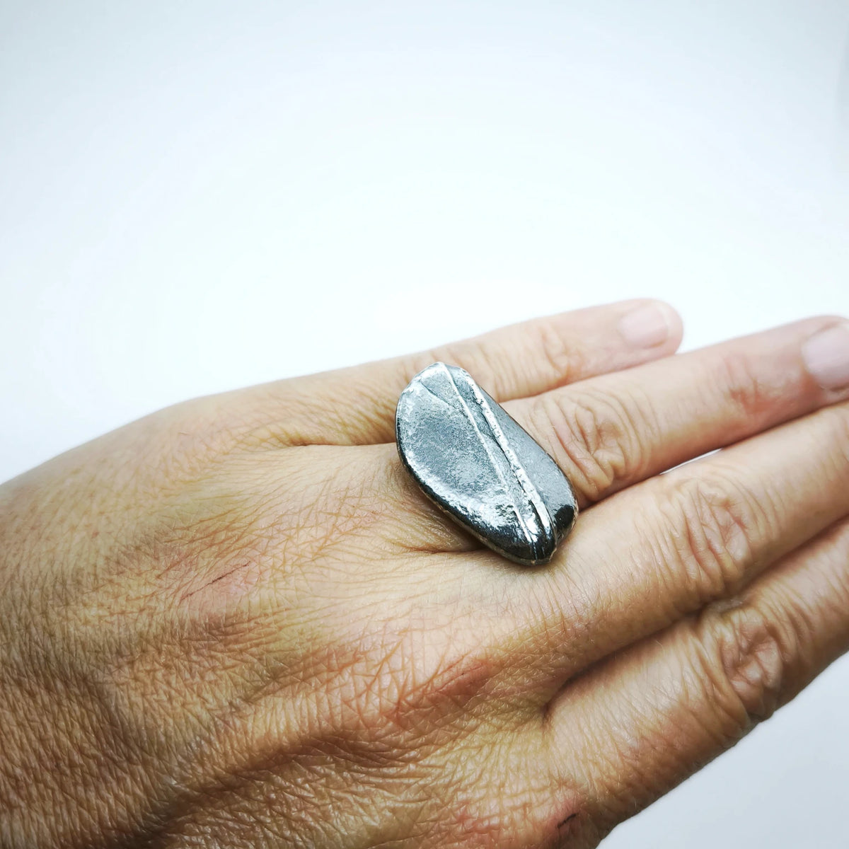 Woman wearing a 925 sterling silver oxidised ring with the texture from small pebble. Design by Inês Almeida