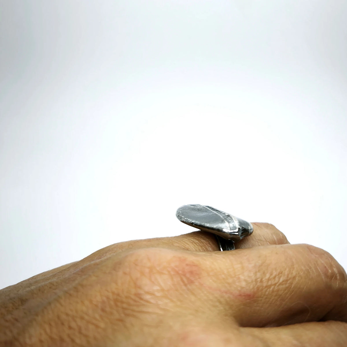 Woman wearing a 925 sterling silver oxidised ring with the texture from small pebble. Design by Inês Almeida