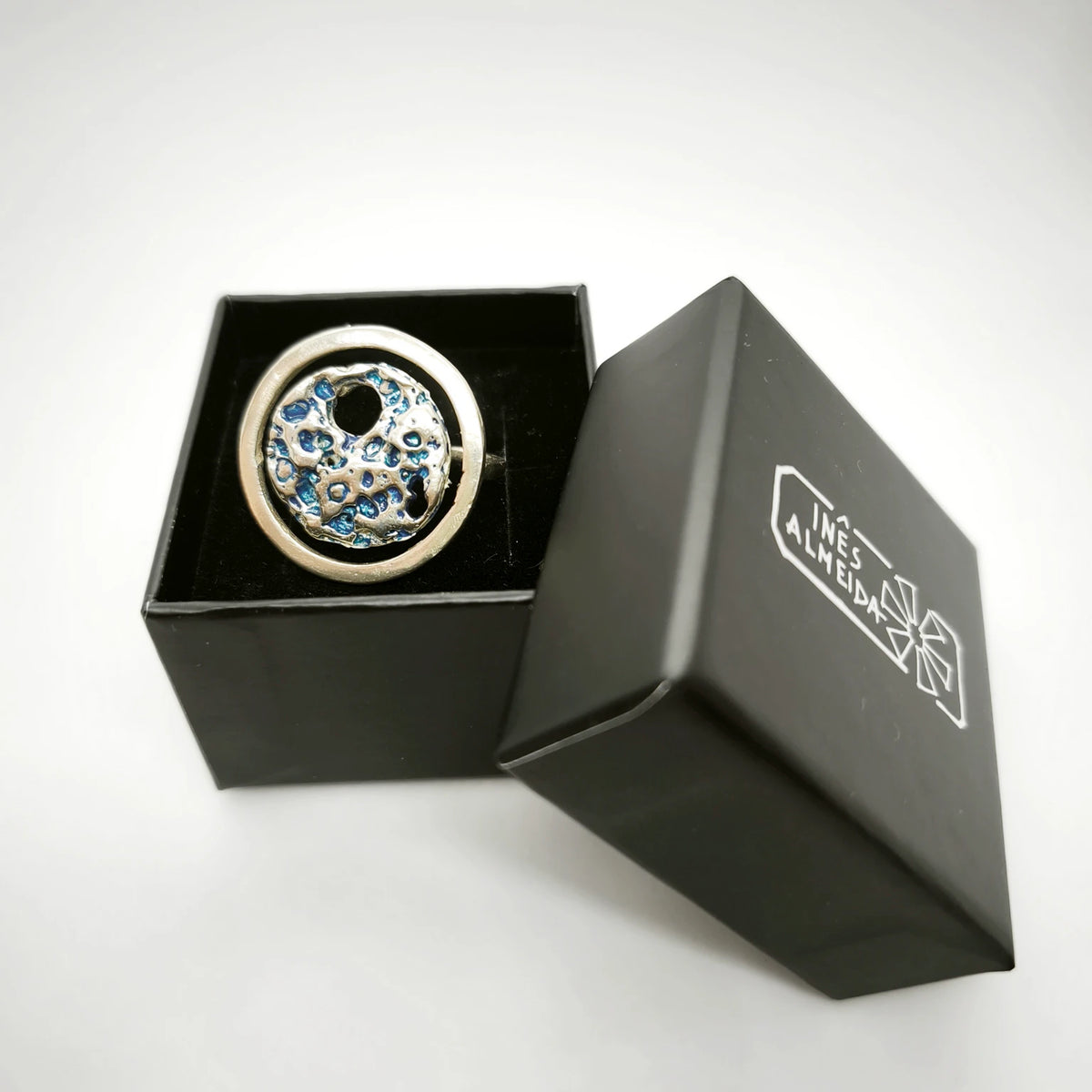 925 sterling silver ring with the texture from a shell painted with blue n a jewellery back box. Design by Inês Almeida