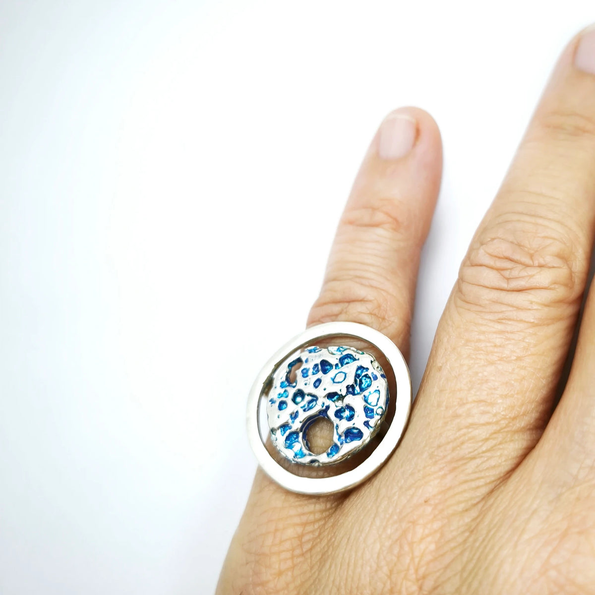 woman wearing a 925 sterling silver ring with the texture from a shell painted with blue. Design by Inês Almeida