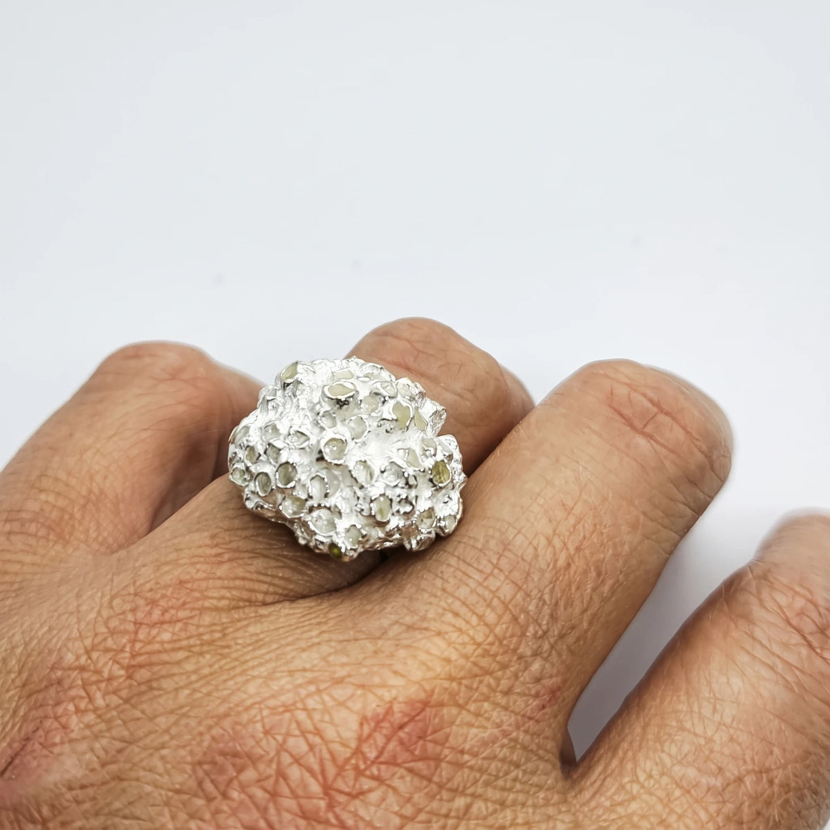 Woman wearing a 925 sterling silver ring with the texture from small barnacles. Design by Inês Almeida