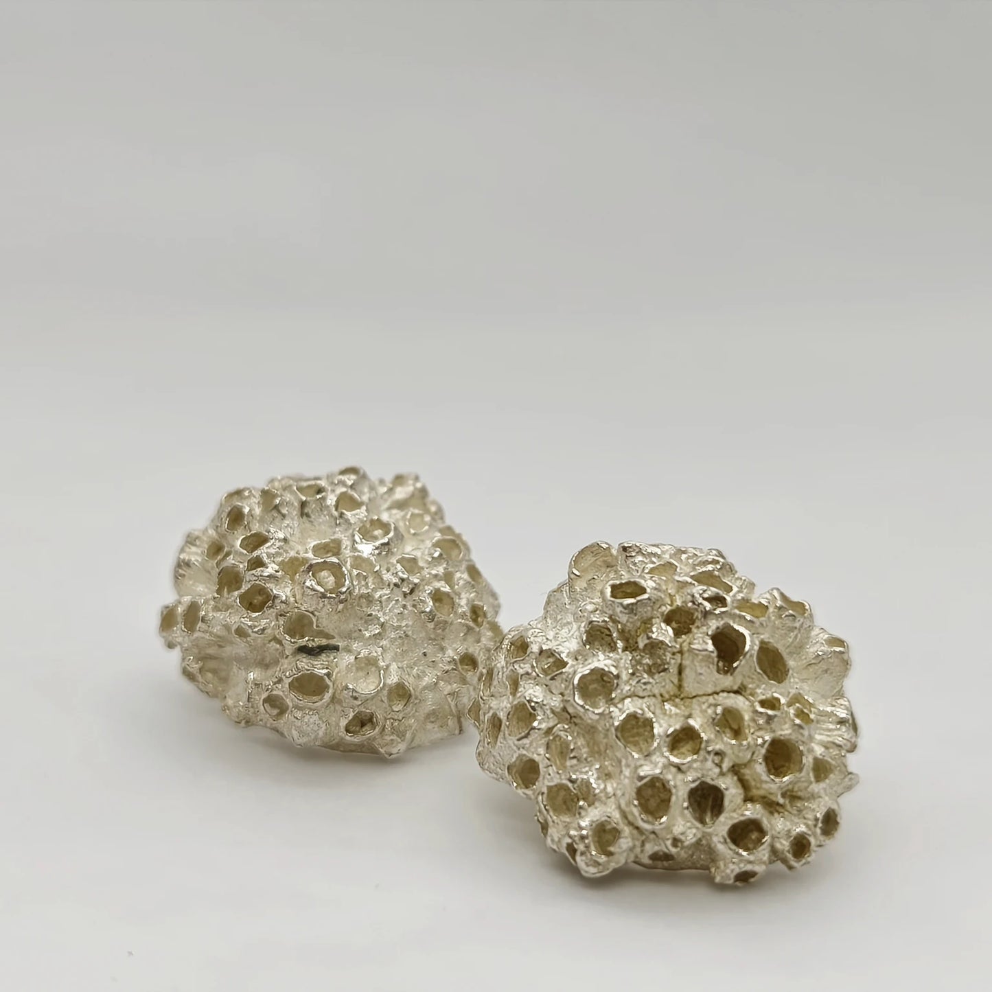 Handcrafted 925 sterling silver earrings with organic texture inspired by marine barnacles, set against a neutral background. Piece by Inês Almeida Jewellery