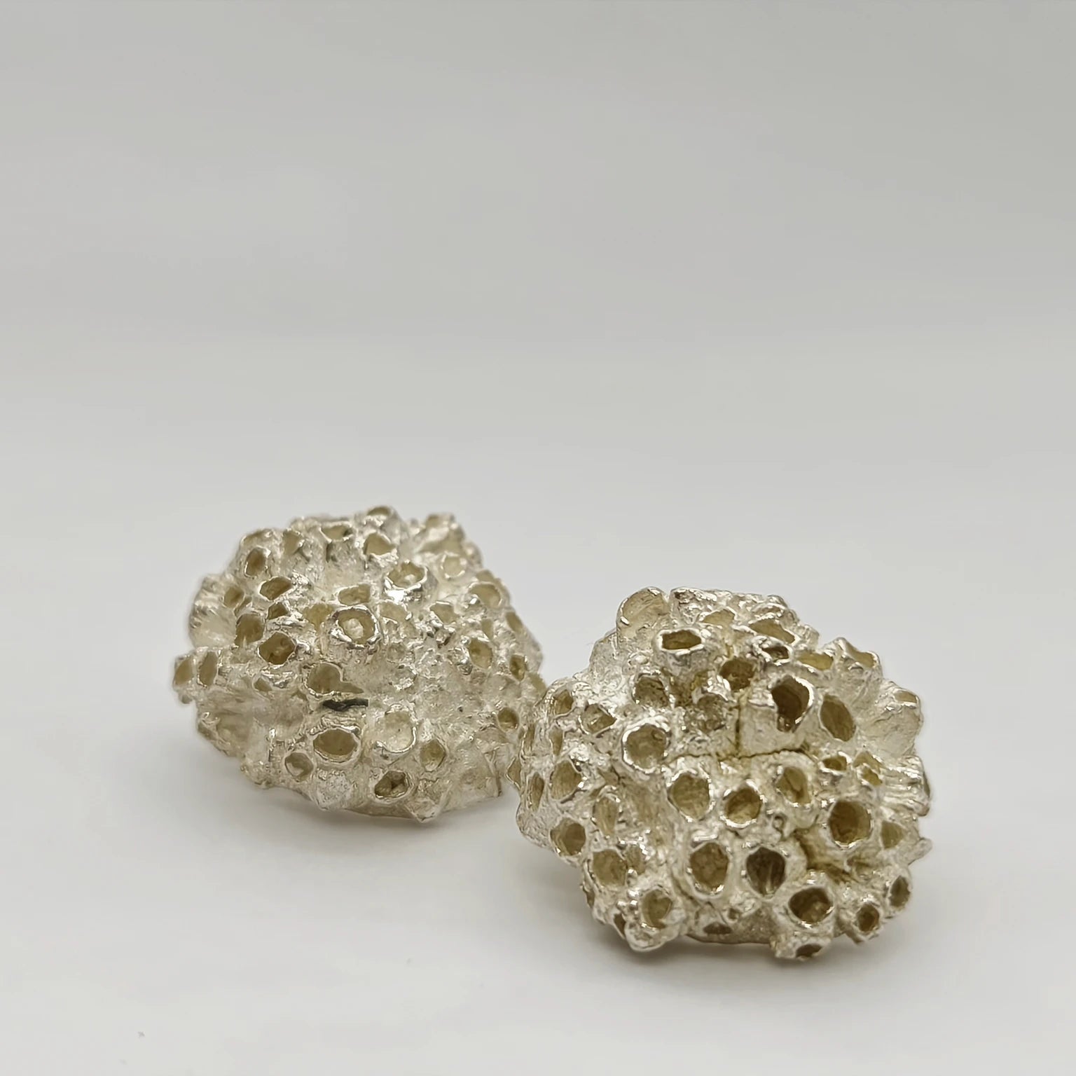 Handcrafted 925 sterling silver earrings with organic texture inspired by marine barnacles, set against a neutral background. Piece by Inês Almeida Jewellery
