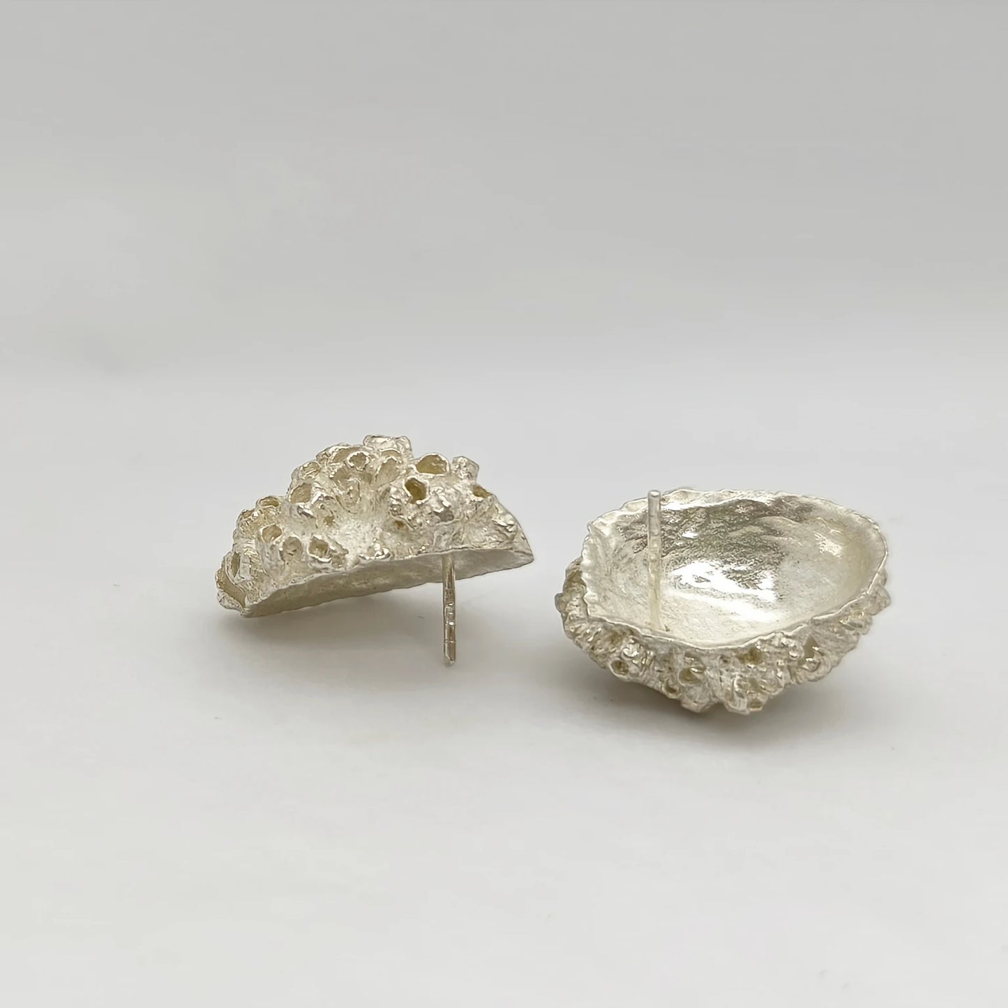 Handcrafted 925 sterling silver earrings with organic texture inspired by marine barnacles, set against a neutral background. Piece by Inês Almeida Jewellery