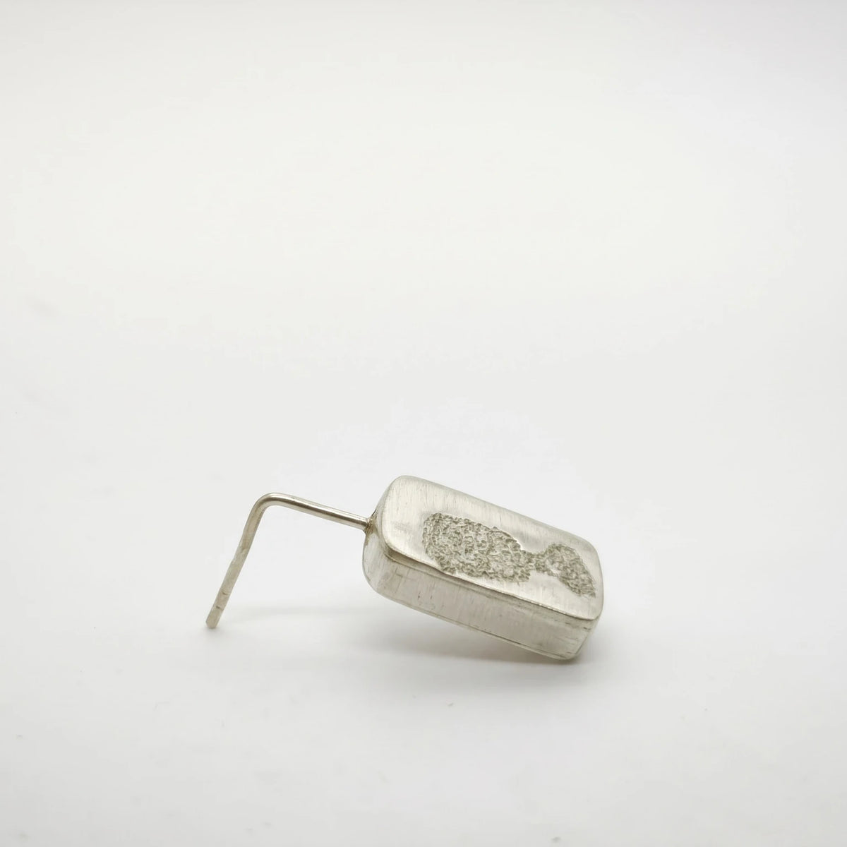 Profile view of a sterling silver drop earring featuring a black glass motif, showing its depth and hook fastening, by Inês Almeida.