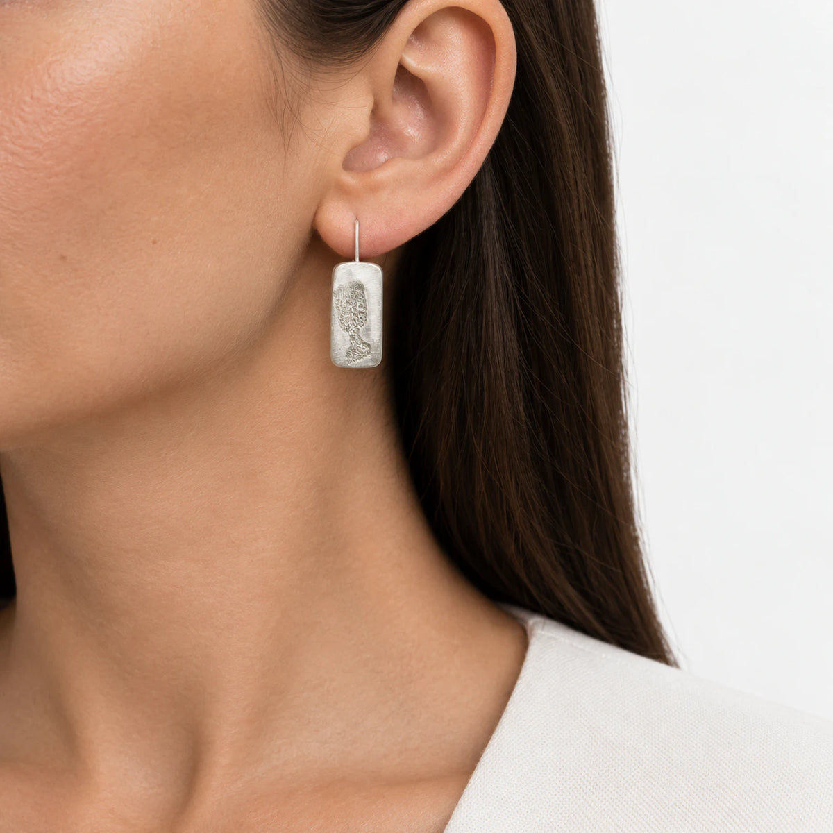 Sterling silver drop earring featuring a black glass motif worn on the ear, shown in a close-up contemporary jewellery portrait against a soft white background, by Inês Almeida.