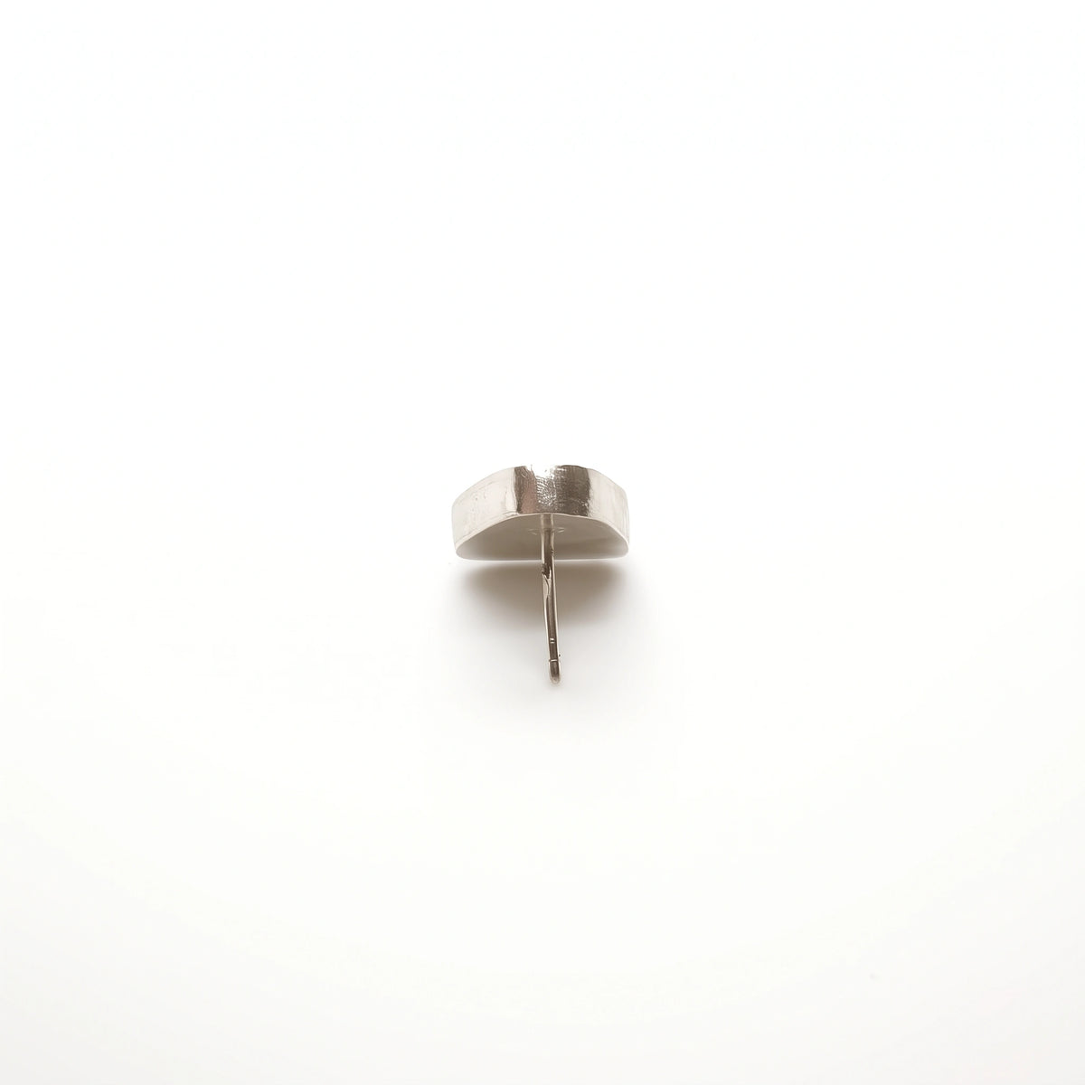 Back view of a sterling silver earring featuring a bottle motif, showing its depth and post fastening, by Inês Almeida.
