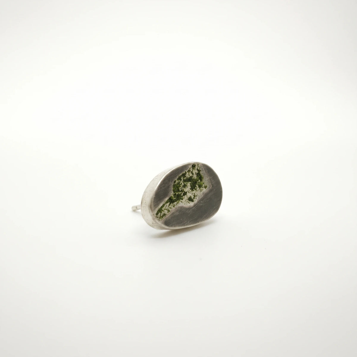 Angled view of a sterling silver earring featuring a green bottle motif, by Inês Almeida.