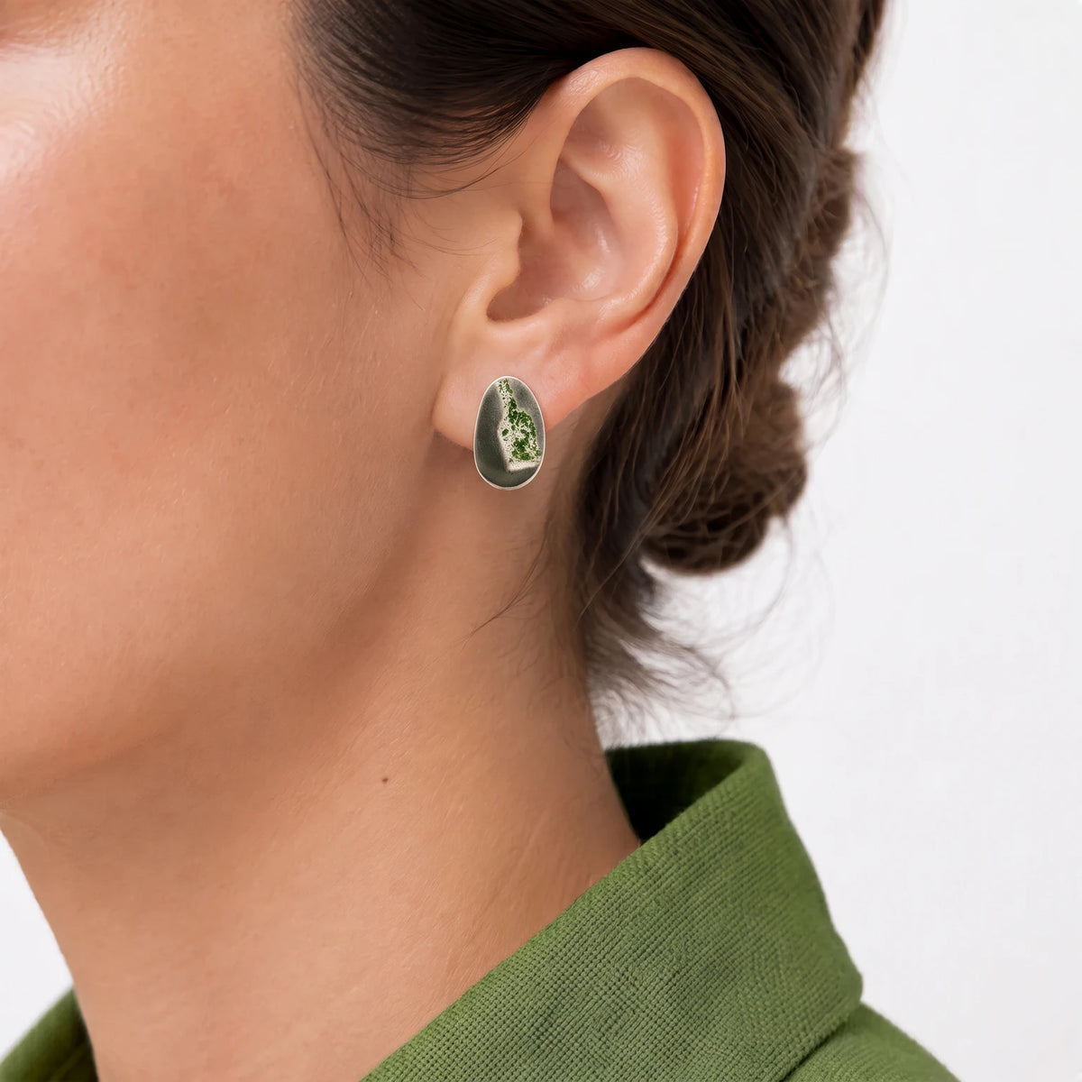 Sterling silver earring featuring a green bottle motif worn on the ear, shown in a close-up contemporary jewellery portrait against a soft white background, from the At the Table with Morandi collection by Inês Almeida.