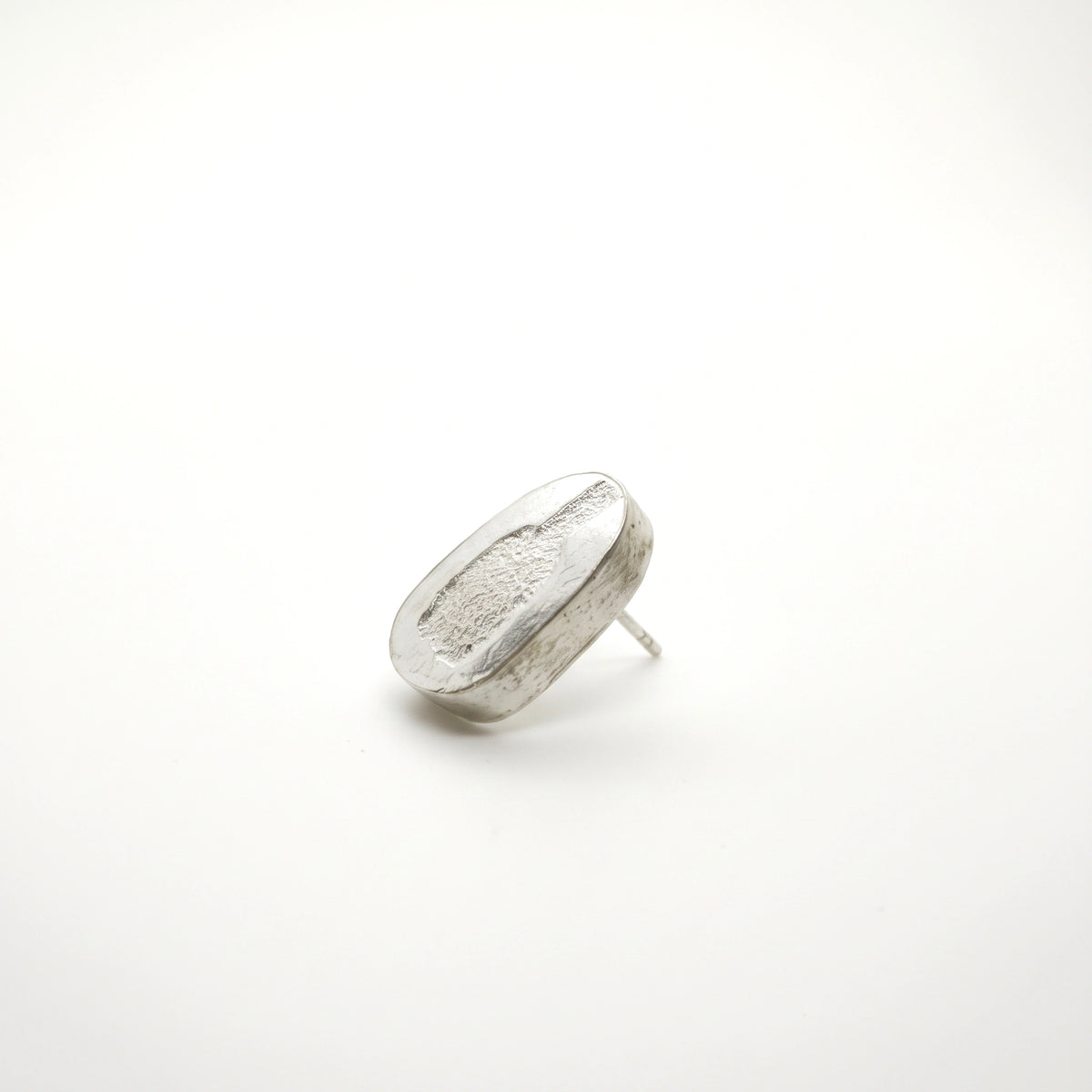 Profile view of a sterling silver earring featuring a jug motif, showing its depth and post fastening, by Inês Almeida.