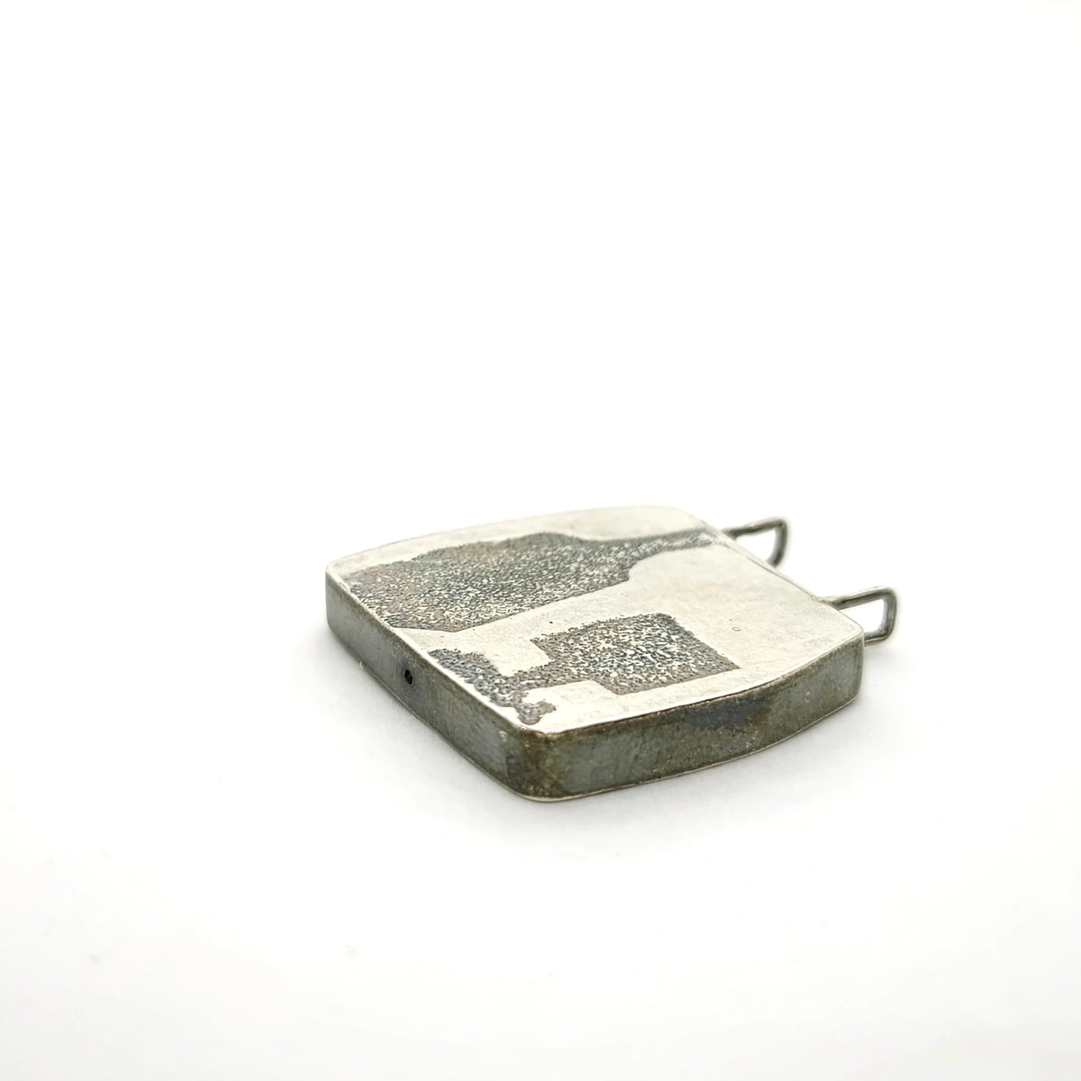 Angled view of a sterling silver pendant featuring a bottle and glass motif, by Inês Almeida.