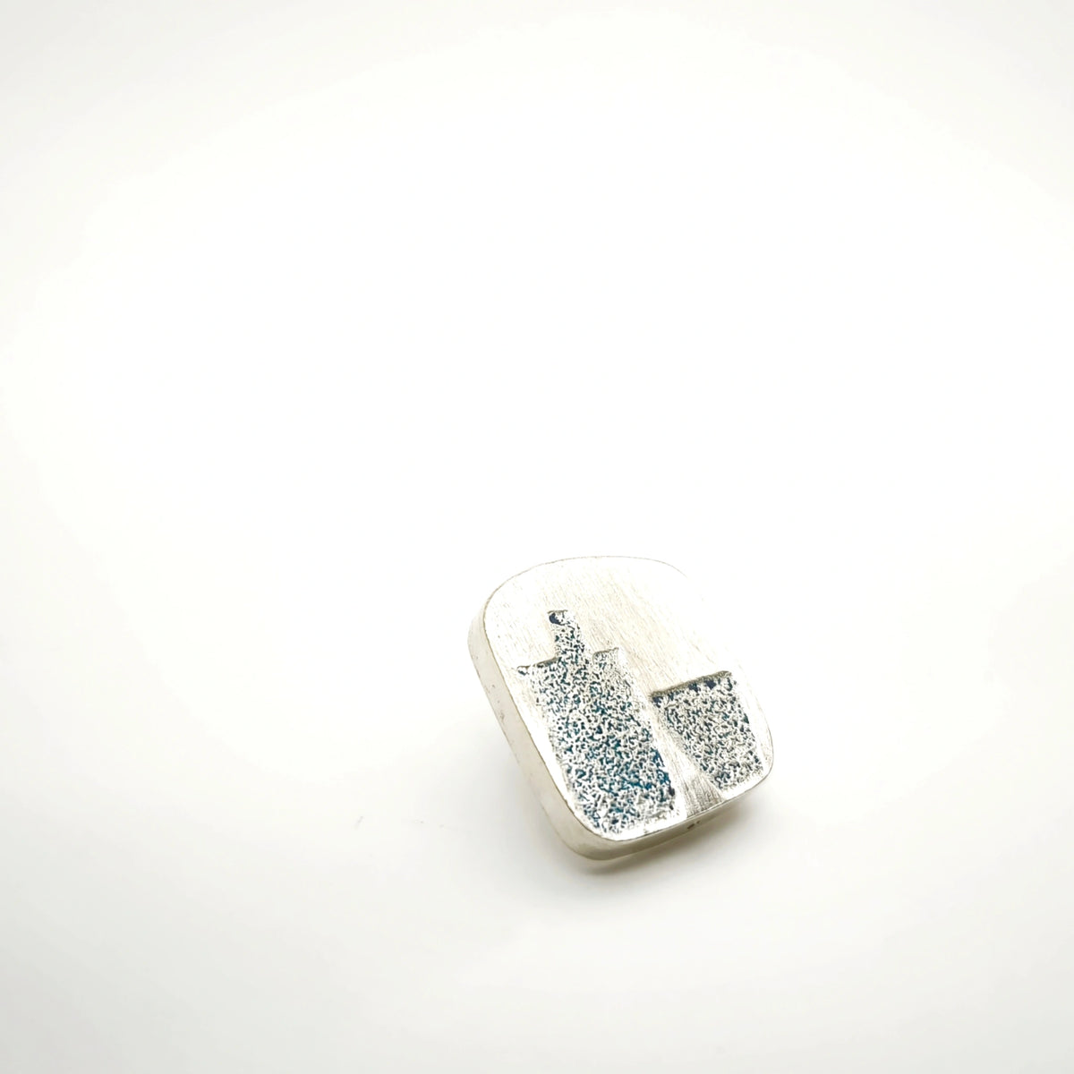 Angled view of a sterling silver pin featuring a blue bottle and glass motif.