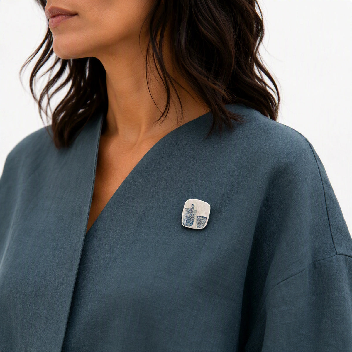 Sterling silver pin featuring a bottle motif worn on an blue contemporary garment, from the At the Table with Morandi collection.